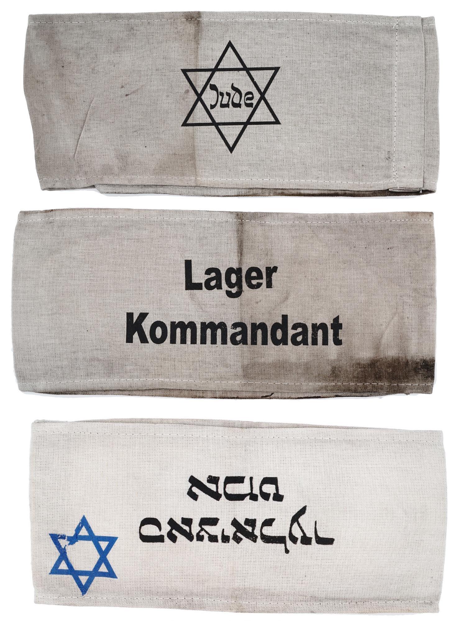 GROUP OF 3 HOLOCAUST JEWISH GHETTO ARMBANDS: A collection of three World War II Jewish Holocaust Ghetto armbands. The collection includes a Jude armband, a Lager Kommandant, Camp Commander, armband, and a Social Worker armband, inscribed in Hebr