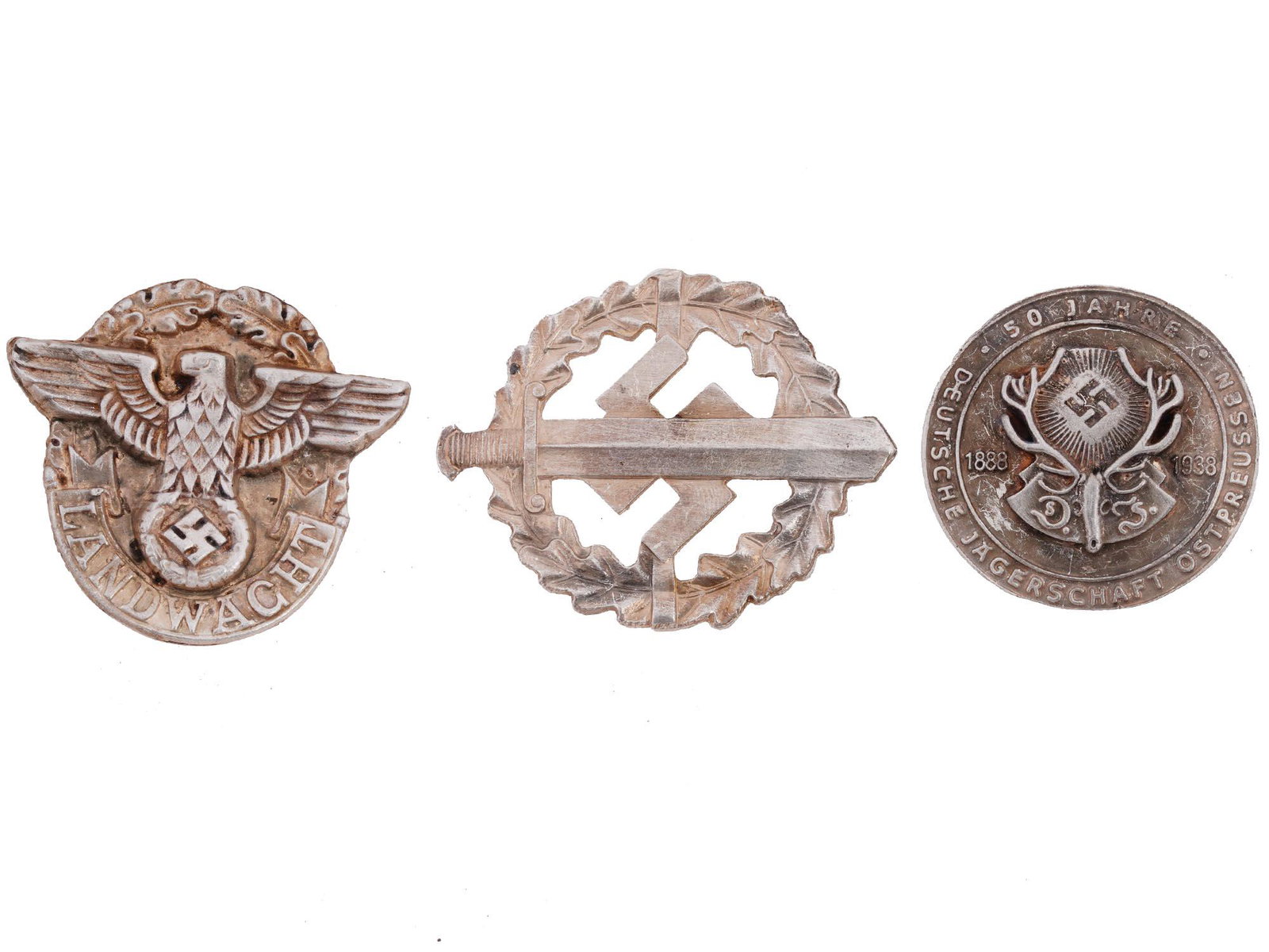 GROUP OF 3 GERMAN WWII BADGES: A lot of three World War II Nazi German military decorations. SA Sport award in silver, Deutsche Jagerschaft Ostpreussen Hunting Society 50 years anniversary commemorative badge, Landwacht badge. Seco