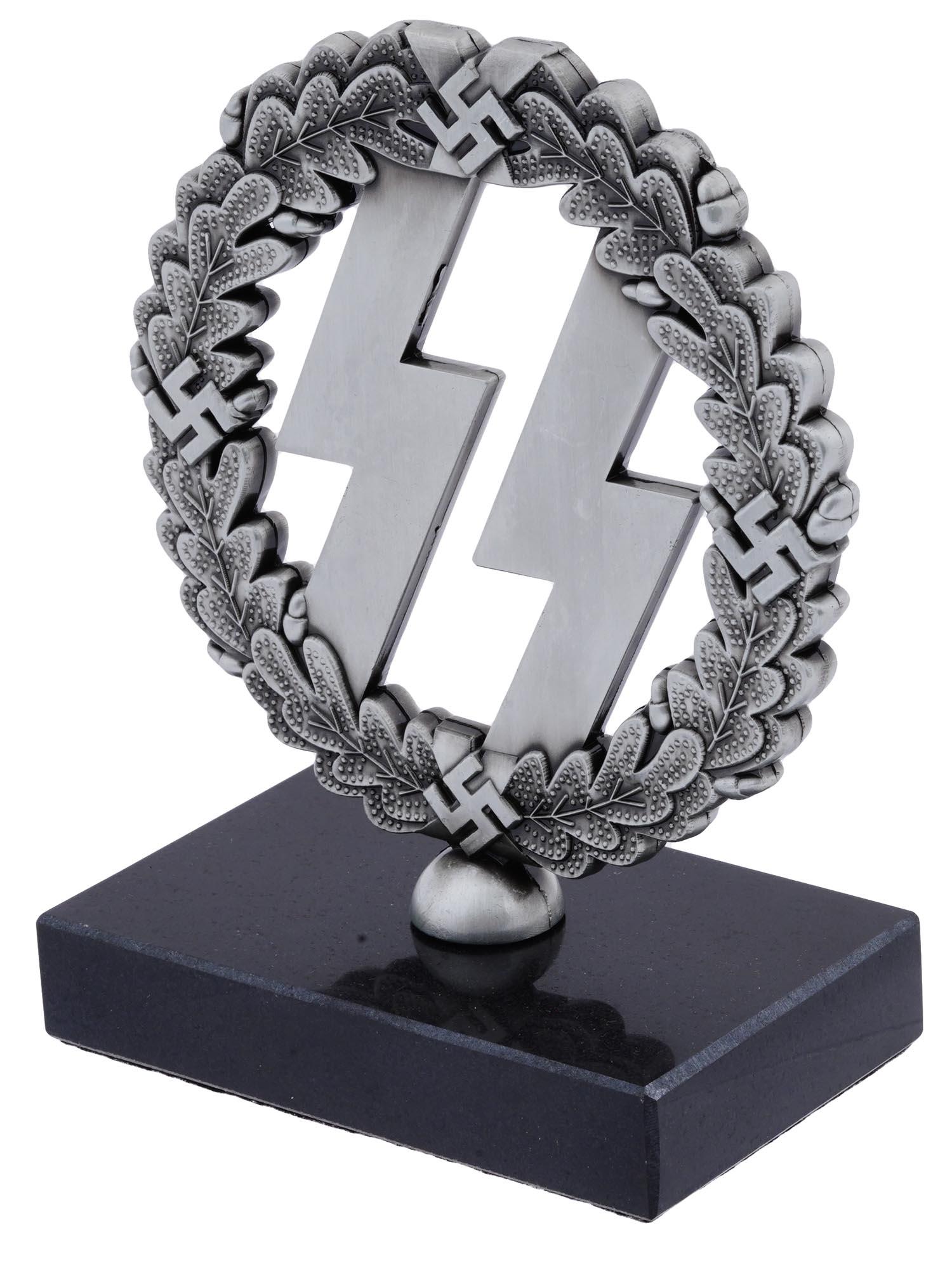 WWII NAZI GERMAN SS RUNES TABLE STAND SCULPTURE: A World War II Nazi German Third Reich patriotic steel desk decor sculpture. The sculpture depicts the SS symbol encompassed by oak leaves with swastikas. Mounted on a black stone base. The Schutzstaf