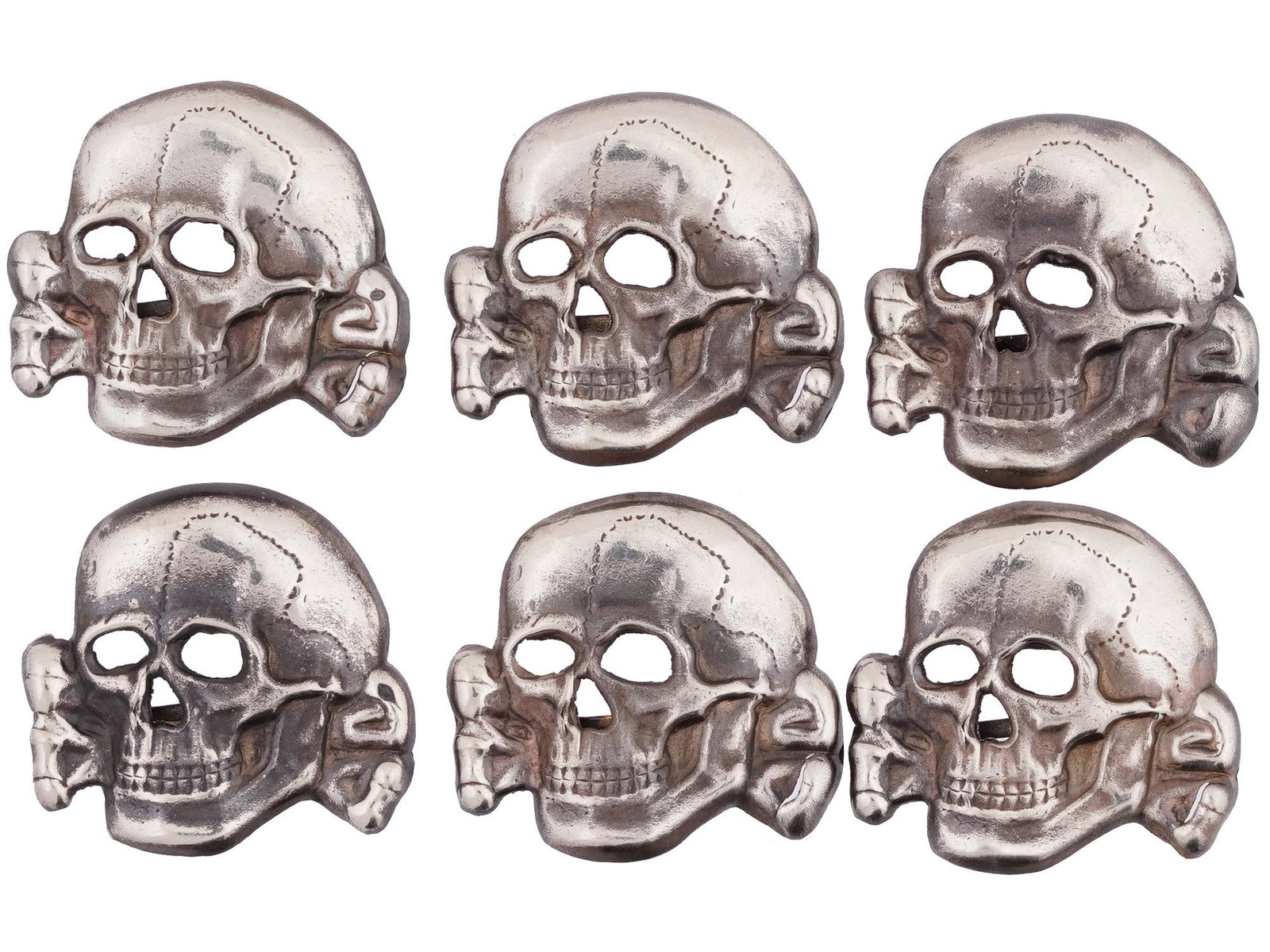 GROUP OF SIX GERMAN WWII SS TOTENKOPF INSIGNIAS: A collection of six WWII Nazi German Third Reich Waffen SS Totenkopf metal swastika insignias. The insignias are made in the shape of a Totenkopf skull. WWII Era German Nazi Pins, Shields, Plaques, Mi