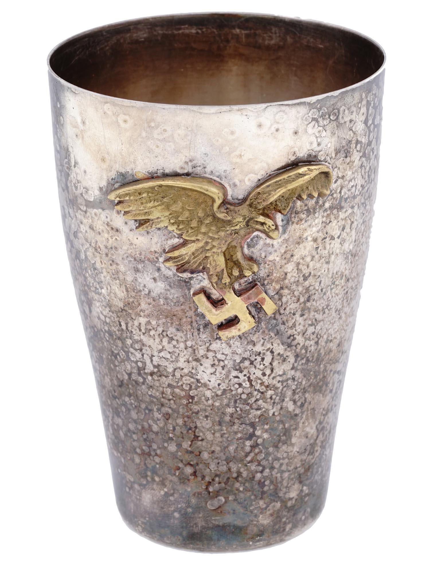 GERMAN WWII LUFTWAFFE PILOTS PRESENTATION CUP: A WWII Nazi German Luftwaffe Pilots presentation cup. The cup is made in a chased design, and adorned with a relief gilded plaque, made in a shape of a Nazi eagle holding a swastika insignia. Marked w