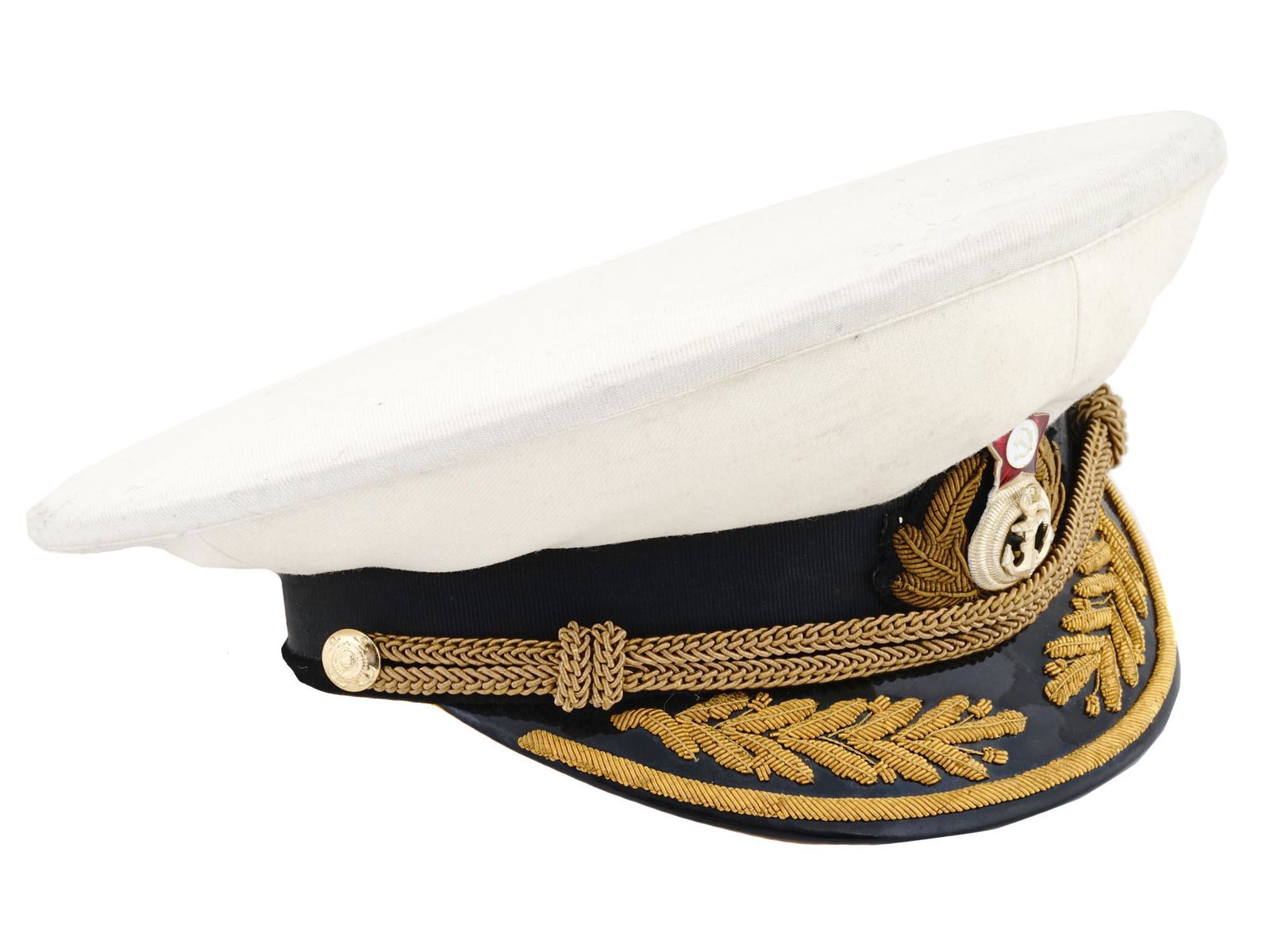 SOVIET ADMIRALS WHITE DRESS UNIFORM VISOR HAT: A Soviet admirals white dress uniform visor hat featuring a white fabric cover, a black visor, and a gold colored insignia on the front that signifies the rank and branch of service, with a red enamel