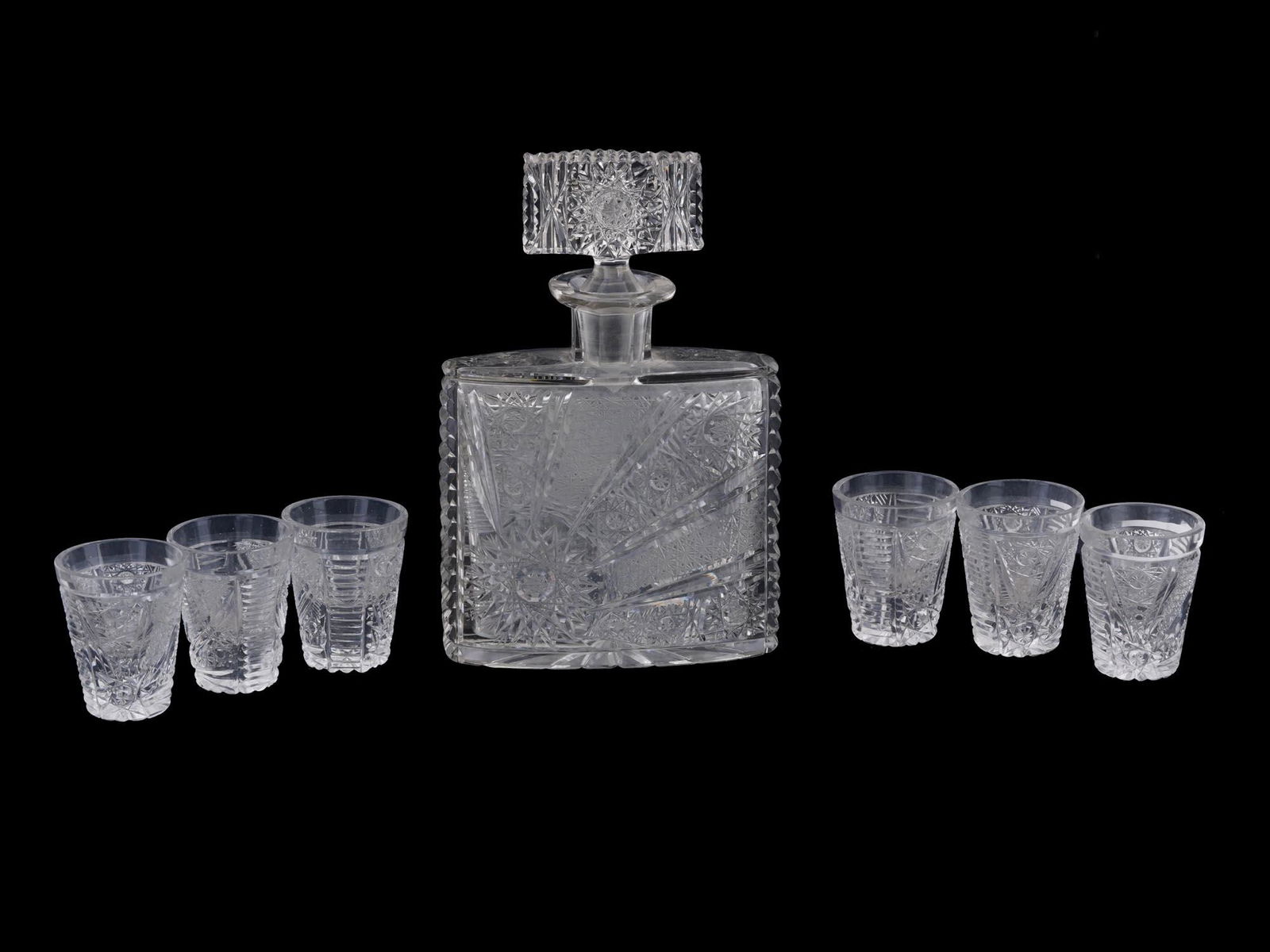 VINTAGE CUT CRYSTAL DECANTER AND SHOT GLASSES: A vintage cut crystal barware set. A total of 7 items, a decanter with stopper and 6 shot glasses. Hobstar and prism motifs. Collectible Glassware, Tableware And Serveware. Dimensions: Overall size: (