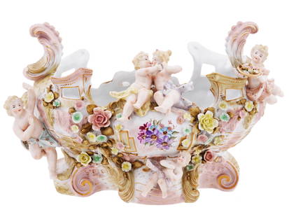 VINTAGE GERMAN MEISSEN PORCELAIN CENTERPIECE CHERUBS: A vintage German Meissen porcelain centerpiece modeled as a boat and features exquisite hand paintings with gilt details. The boat is adorned with applied cherub figurines, adding a touch of whimsy an