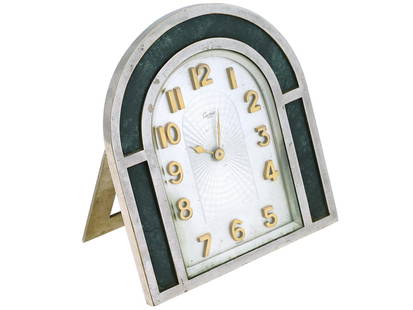 MIDCENT STEEL AND GREEN MARBLE CARTIER DESK CLOCK: A mid-20th century stainless steel standing table clock by Cartier. Arch shape, green marble inset along the rim. Silver-tone guilloche dial with gilt Arabic numerals and hallmark Cartier Paris. Marke