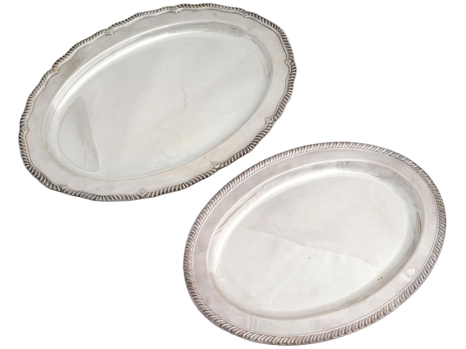 MID CENTURY OVAL SILVER PLATED SERVING TRAYS: A pair of mid-20th century silver-plated serving trays. Oval shaped, embossed rim decor. Collectible Silverplate, Tableware And Serveware. Dimensions: Largest item 18 3/4 x 13 in. All measurements are