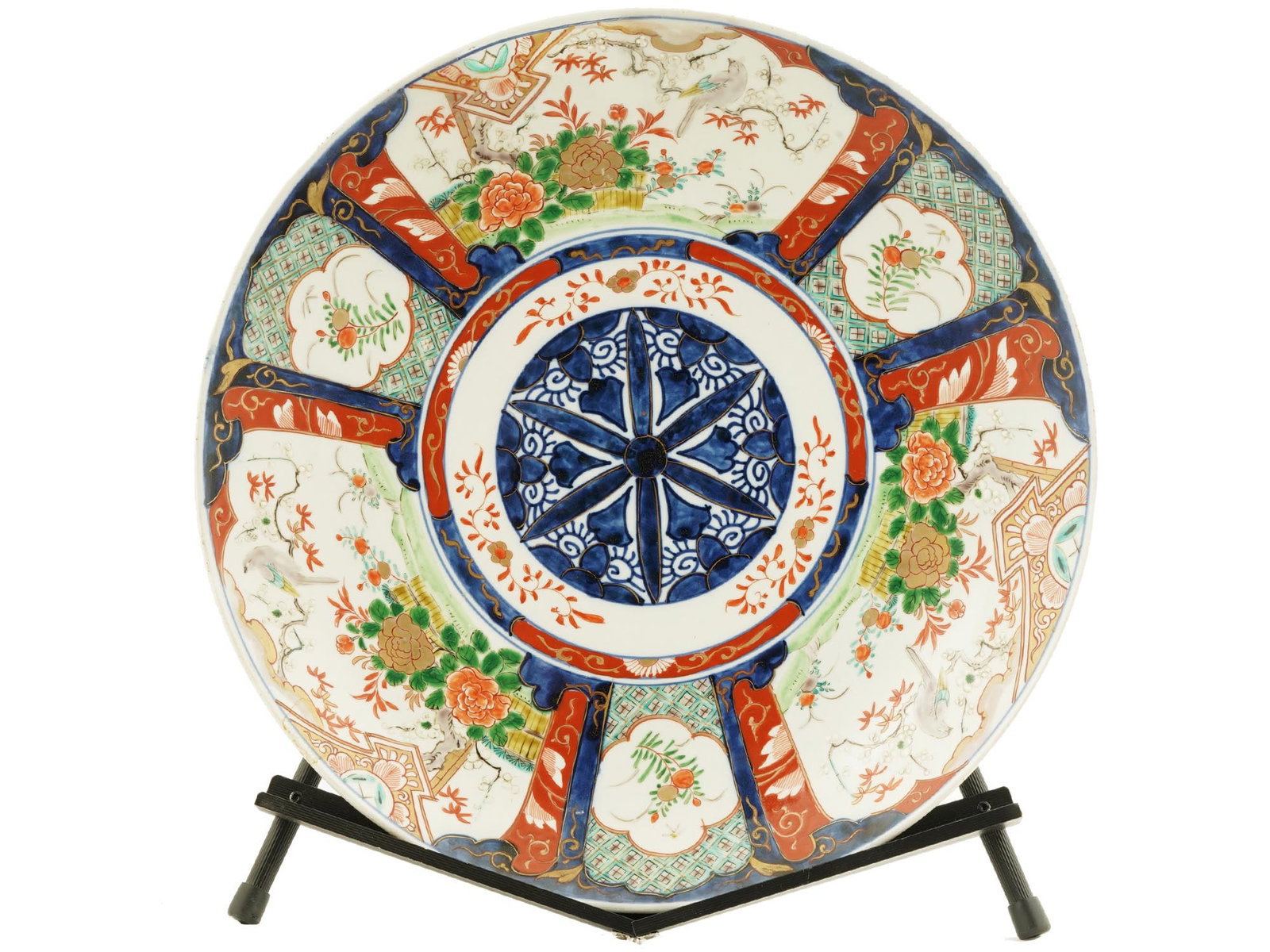 ANTIQUE JAPANESE MEIJI IMARI PORCELAIN CHARGER: An antique Japanese late Meiji period Imari porcelain charger plate with a hand painted floral design in the traditional Imari colors. On a wooden stand. Dates to the late 19th century. Antique Japane