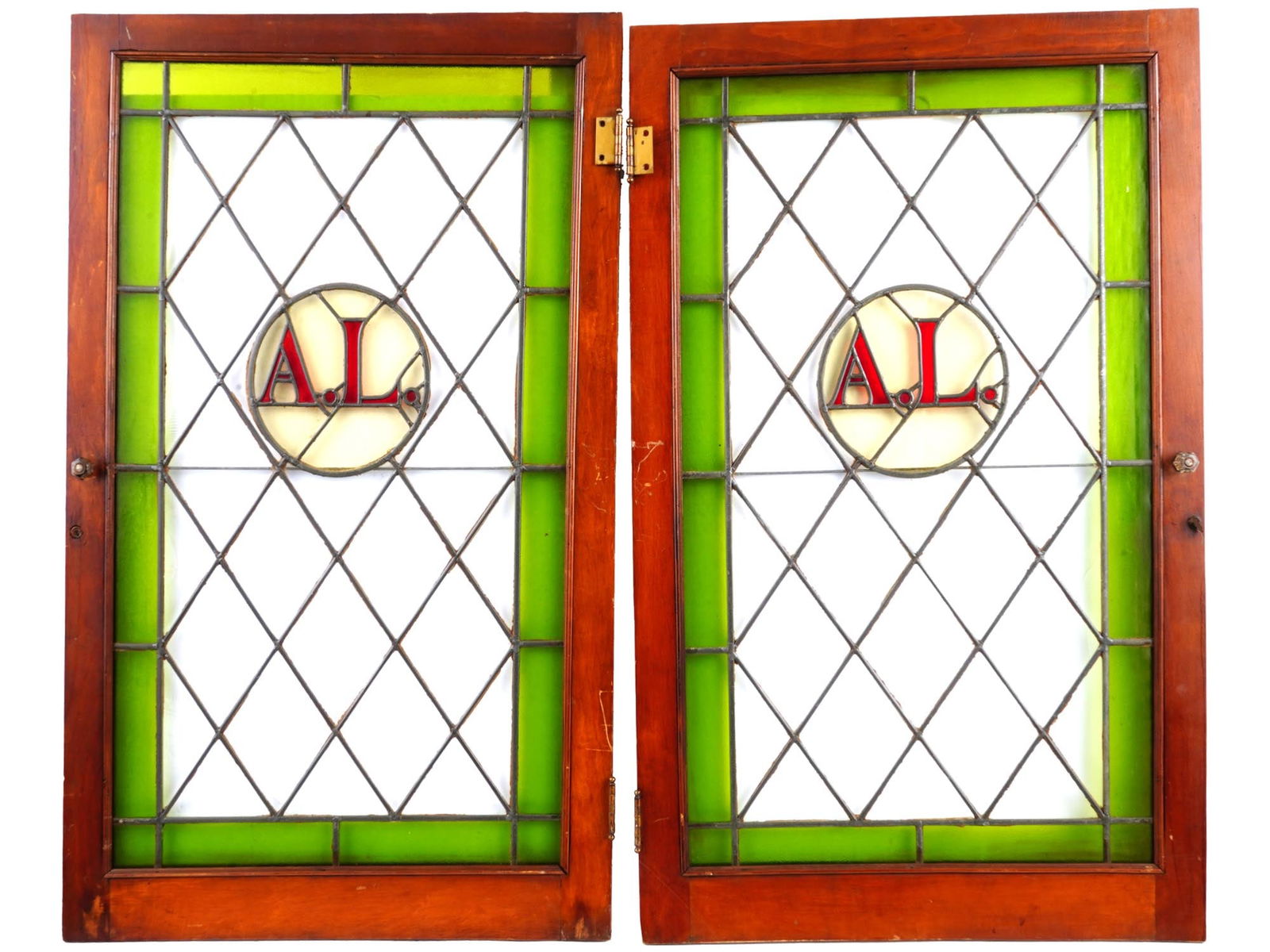 ART NOUVEAU MONOGRAM STAINED GLASS WINDOW PANELS: A pair of identical vintage leaded stain glass windows. Each window is adorned with a geometrical pattern with variations of texture and color, and a monogram, A. L.. Circa: the first half of the 20th