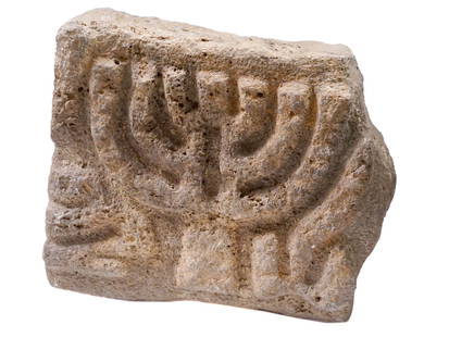 ANCIENT MENORAH PIECE CARVED FROM BASALT STONE: An ancient menorah piece carved from basalt stone. The menorah is a seven-branched candelabrum that holds deep symbolism in Jewish tradition. It was a prominent fixture in the Holy Temple in Jerusalem