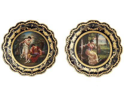 NEOCLASSICAL ROYAL VIENNA PORCELAIN TAZZAS SIGNED: A pair of Neoclassical porcelain tazzas or footed serving plates by Royal Vienna, an Austrian porcelain manufacturer. The black rim with gilt ornaments encompasses the central part with a hand-painted