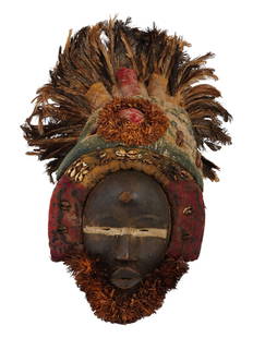 ANTIQUE AFRICAN IVORY COAST CARVED WOOD DAN MASK: A large and very impressive hand-carved baobab wood Dan people helmet mask from the African Coast region, West Africa. The mask is decorated with chicken feathers and cowrie shells. Dan people is a Ma