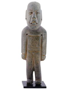 ANCIENT PRE COLUMBIAN OLMEC GREEN STONE FIGURINE: An ancient Pre Columbian Olmec green stone figurine. A standing figure in a simple pose with straight legs and arms straight down. The bald flat topped head and elongated ears with almond shaped eyes