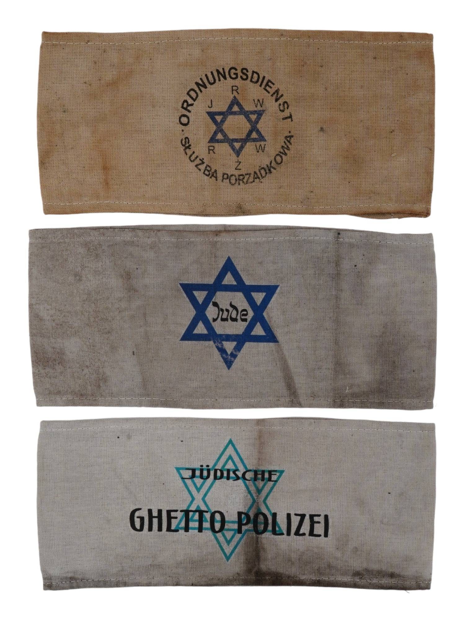GROUP OF 3 HOLOCAUST PERIOD ARMBANDS: A group of three Holocaust armbands. Includes an armband with the inscription Jude within the blue printed Star of David, a Judische Ghetto Polizei, Jewish Ghetto Police armband, and an armband with a