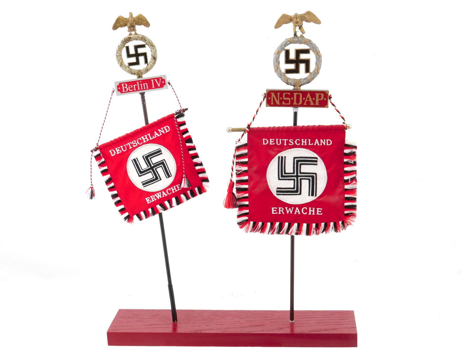 GERMAN WWII NSDAP TABLE STAND WITH 2 FLAGS: A Nazi Germany table stand with two red flags. The flags are of different sizes and have a similar design with red, white and black stripes along the edges and tassels on the laces. Both flags feature