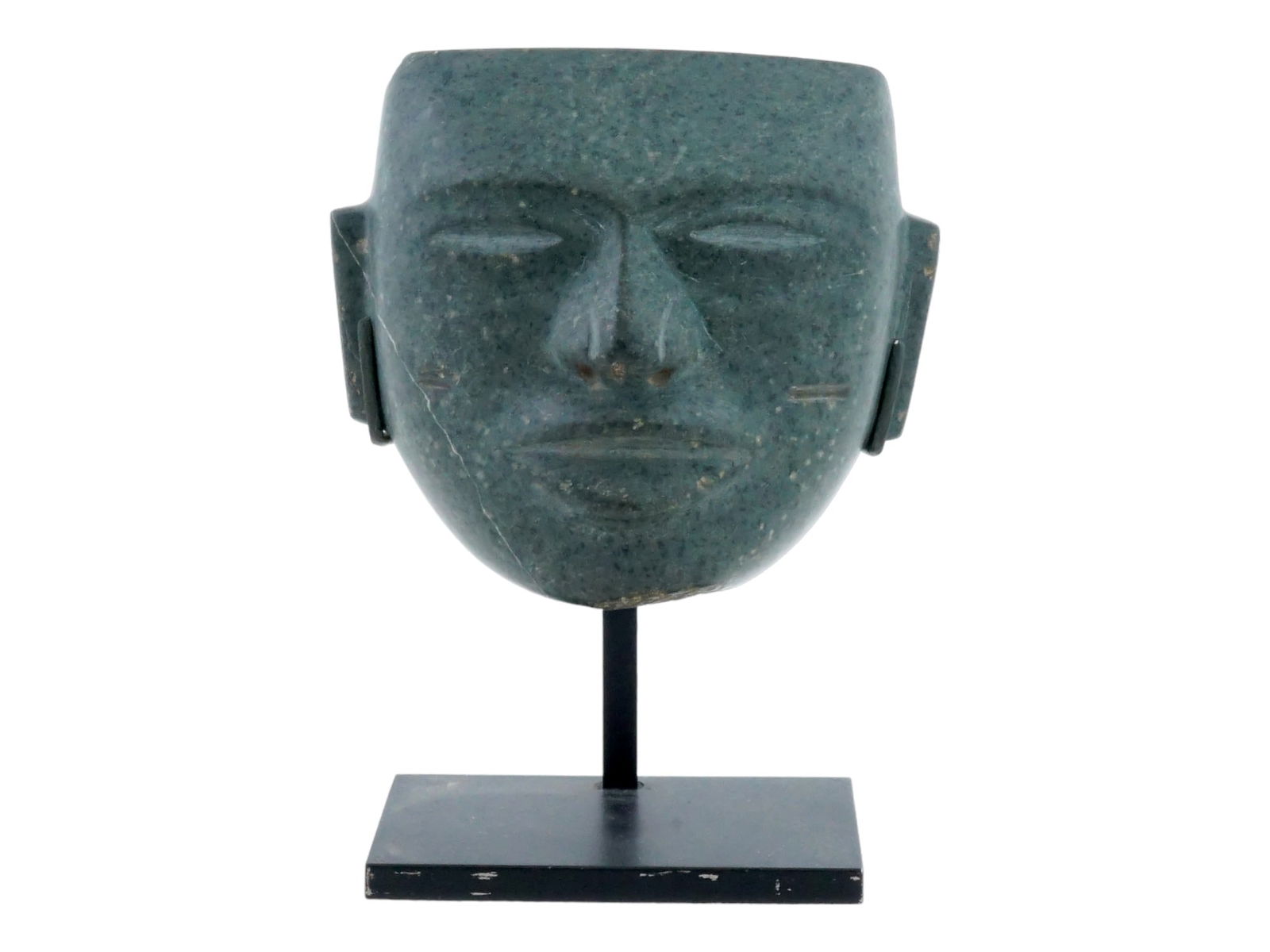 ANCIENT MESOAMERICAN OLMEC HEAD OF DARK GREEN STONE: An ancient carved Olmec head from Pre Columbian America made of dark green stone. This is a male face with a calm, benevolent expression, featuring narrow eyes and a smile that makes you feel like it