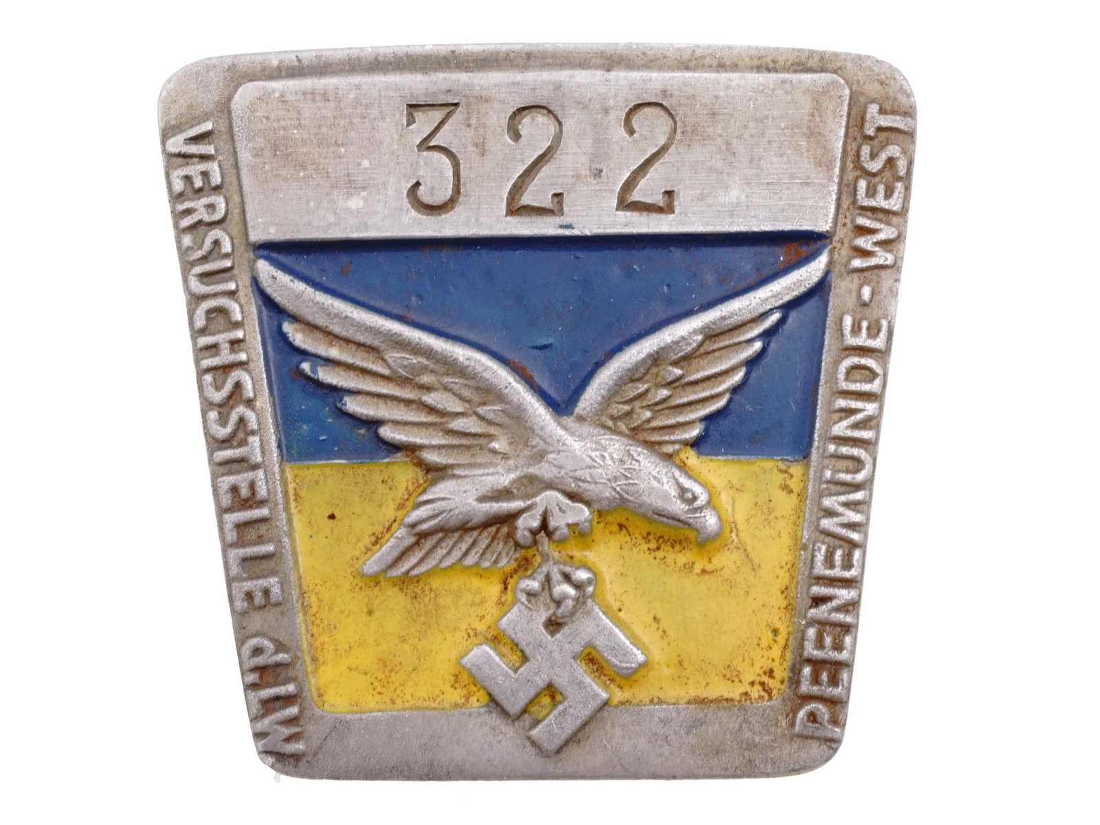 WWII PEENEMUNDE WEST V 2 FACTORY EMPLOYEE BADGE: A rare WWII Nazi German Third Reich Luftwaffe Peenemunde West V 2 factory employee metal badge. The badge is decorated with an engraved eagle swastika insignia, covered with enamel in yellow and blue 