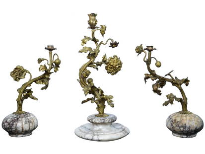 ANTIQUE GILT BRONZE MARBLE BASE DESK CANDLE HOLDERS: Three antique gilt bronze desk candle holders, each meticulously crafted in the form of a graceful plant with intricate flowers. These candle holders stand atop elegant marble bases, combining the opu