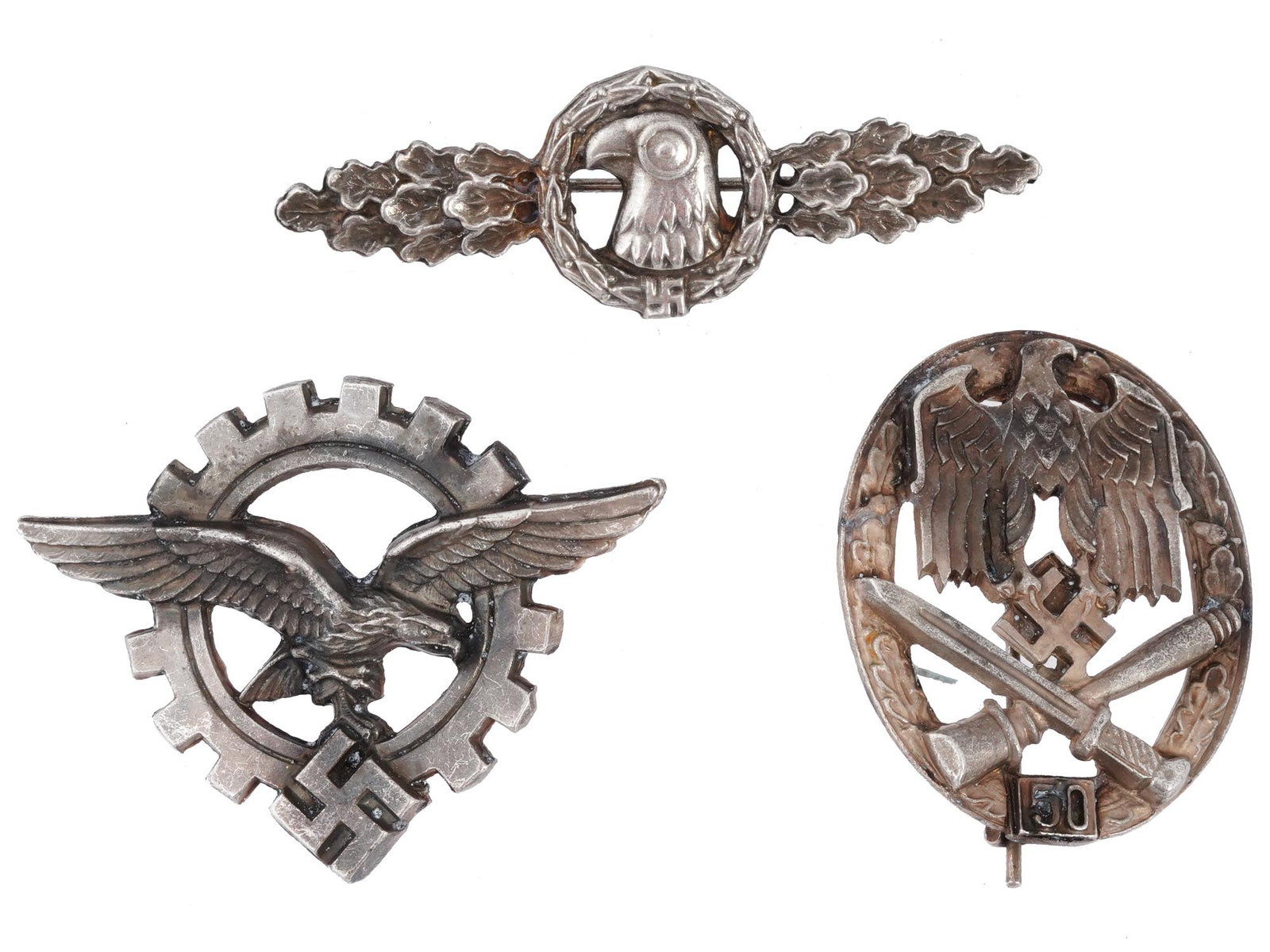 GROUP OF THREE WWII NAZI GERMAN MILITARY BADGES: A group of three WWII Nazi German military badges, comprising an Army General Assault Badge, given for 50 assaults, featuring a prominent Wehrmacht-style eagle grasping a swastika, crossed bayonet, an