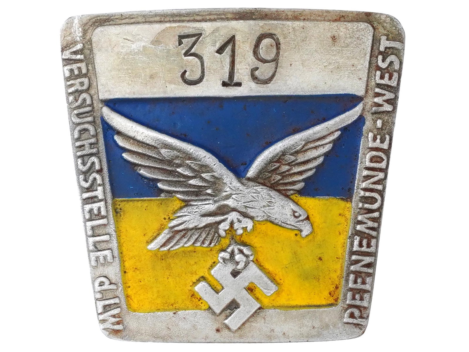 GERMAN WWII PEENEMUNDE V2 FACTORY CONC CAMP BADGE: A WWII Nazi German Third Reich Peenemunde West V 2 factory employee concentration camp metal badge. The badge is decorated with an engraved eagle swastika insignia, covered with enamel in blue and yel