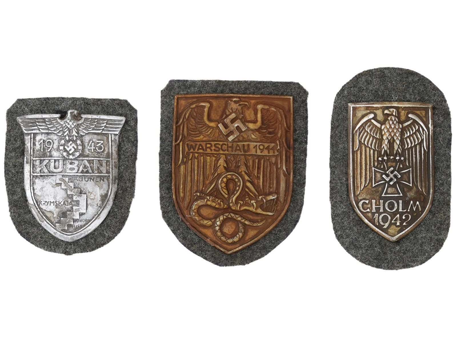 GROUP OF THREE GERMAN WWII SHIELDS: A group of three German WWII shields. The first is the German Kuban Campaign Shield or Kubanschild instituted by Adolf Hitler in 1943. The shield was for award to personnel, in all branches of service