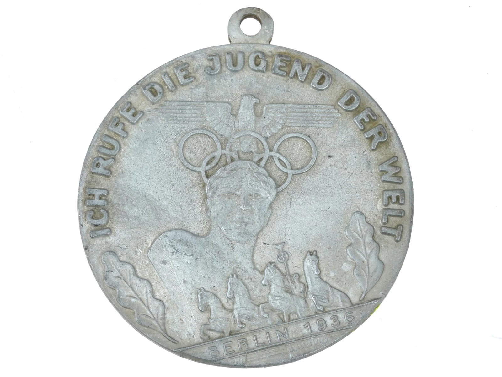BERLIN 1936 OLYMPIC GAMES MEDAL: A 1936 Berlin Summer Olympic Games medal . Inscription in German: Ich Rufe die Jugend der Welt, I Call the Youth of the World, BErlin 1936. Depiction of an athlete, Olympic rings, Reichsadler, and the