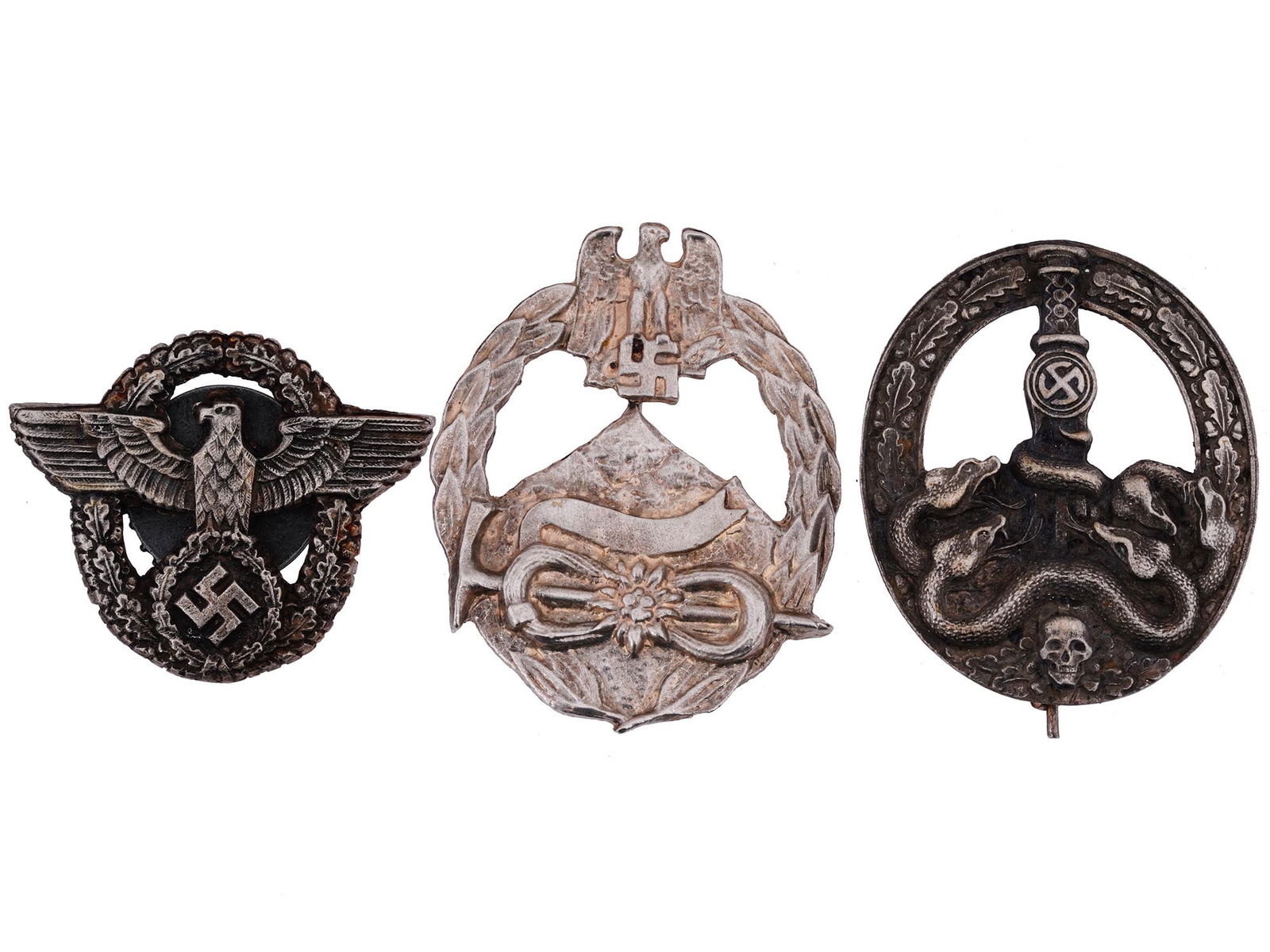 GROUP OF THREE WWII MILITARY BADGES: A group of three WWII military badges including a Bandit Warfare Badge showing a skull and crossed bones at the base, with a laurel wreath of oak leaves around the sides and a sword in the center, wit