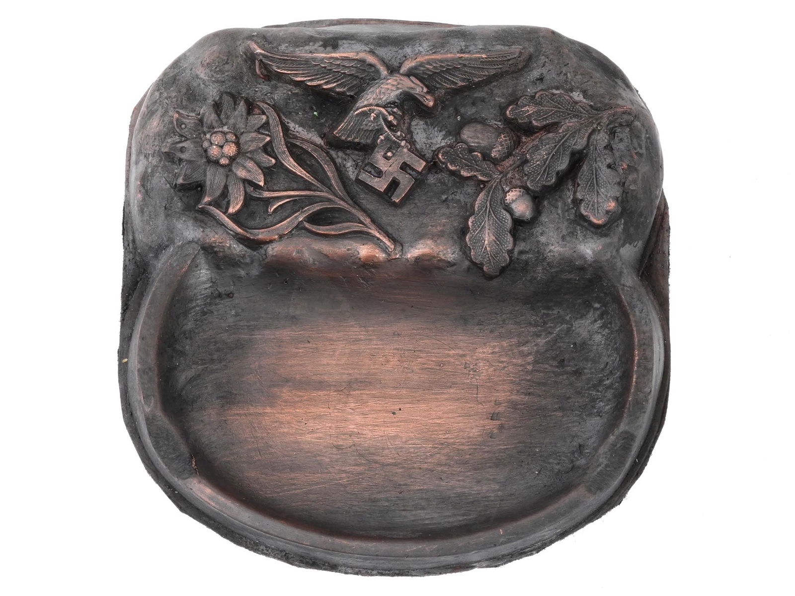 WWII GERMAN THIRD REICH LUFTWAFFE PILOT ASHTRAY: A WWII Nazi German Third Reich Luftwaffe pilot ashtray. The ashtray features relief images of an Edelweiss flower, an eagle with a swastika, and an oak branch with acorns. Fabric on the bottom. Unmark