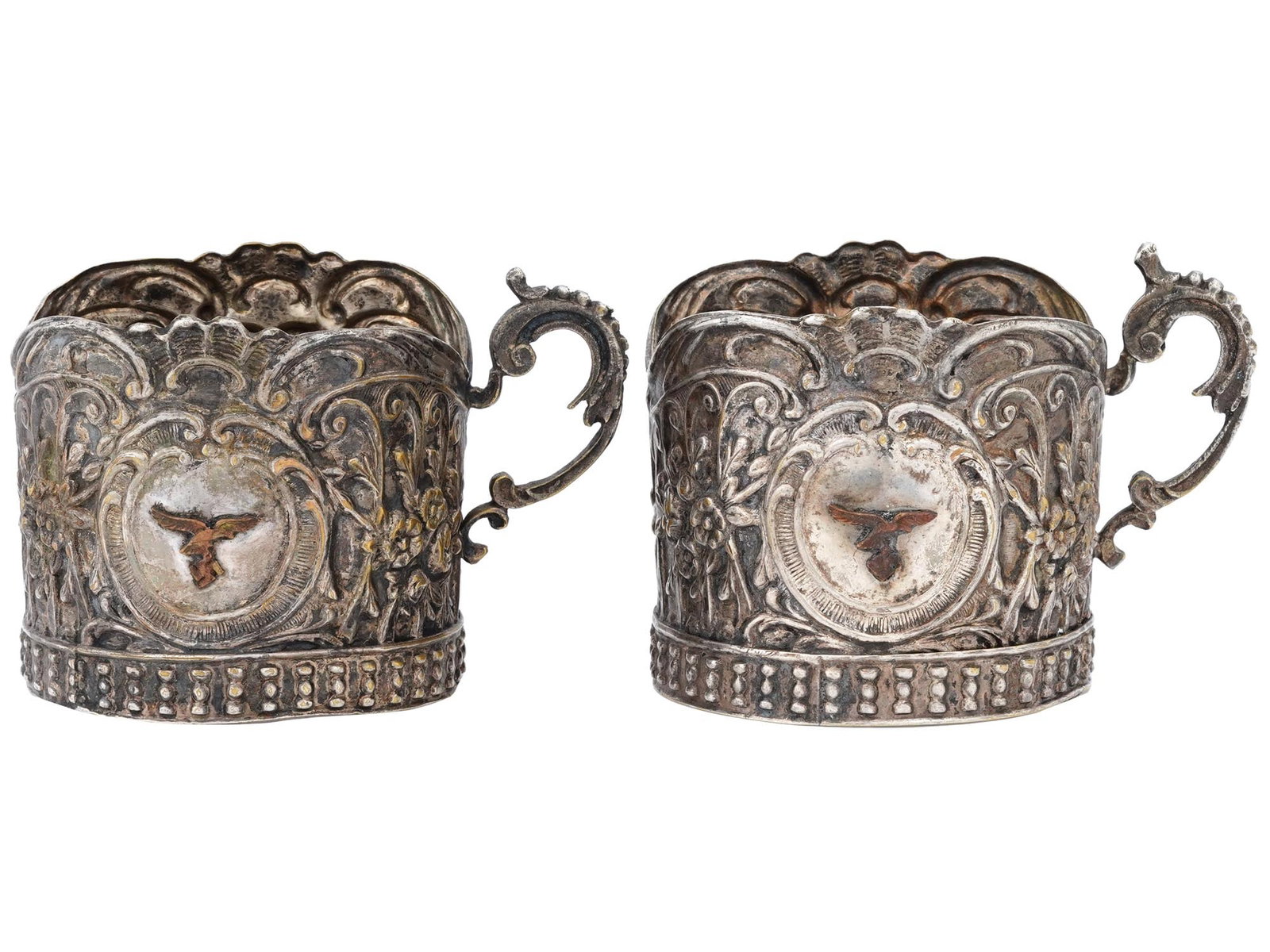 SET GERMAN TEA HOLDERS F LUFTWAFFE PILOTS CANTEEN: A pair of German tea holders from a Luftwaffe pilots canteen. The holders are decorated with floral designs and a German Third Reich eagle with a swastika in cartouche. Marked on the bottom. German Th