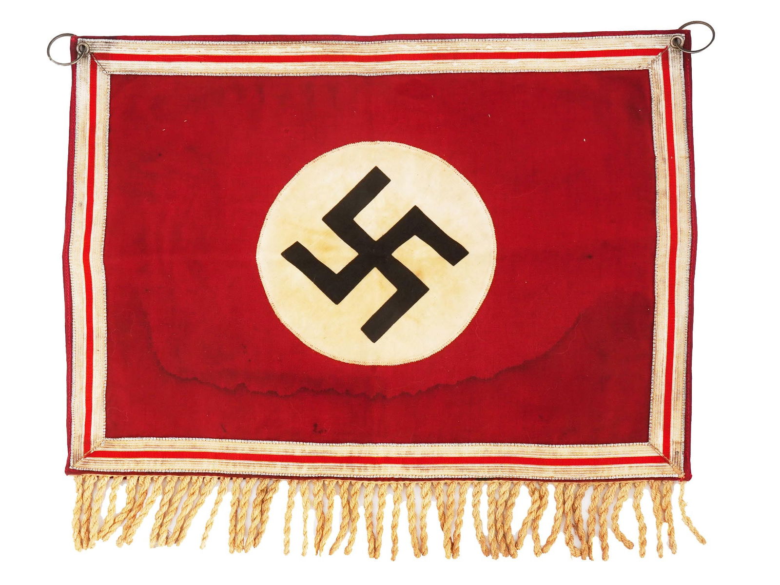 GERMAN THIRD REICH PERIOD NSDAP BANNER: A World War II Nazi German NSDAP banner. The piece is made of red cotton fabric with sewn black and white swastika emblem. Fringe at the bottom, two suspension rings at the top. Second World War Histo