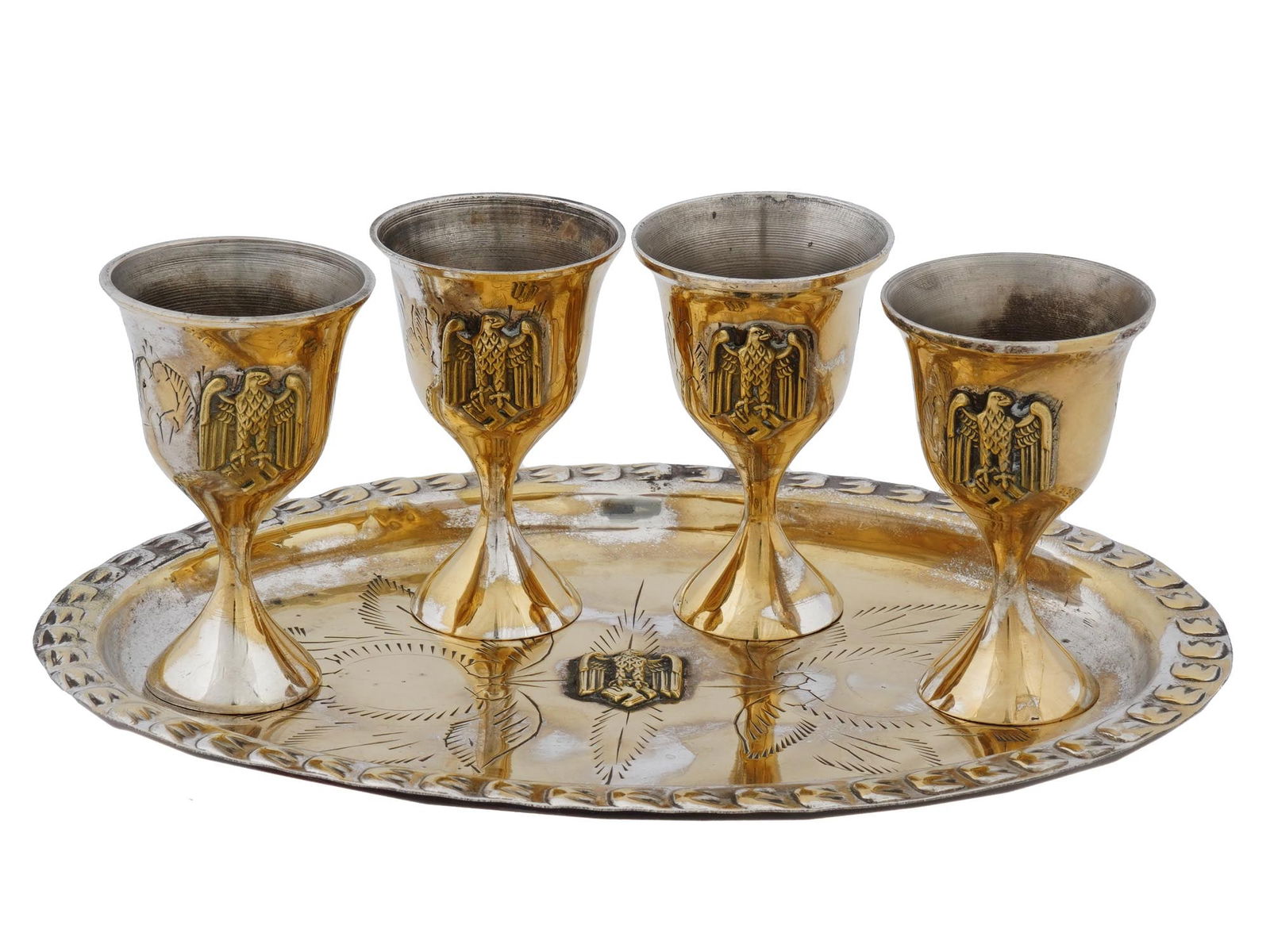 WWII NAZI GERMAN GILT BRASS GOBLETS AND SERVING TRAY: A WWII era Nazi German gilt brass barware set. A total of 5 items, four footed wine cups and a serving tray. The pieces are decorated with overlay Reichsadler emblems and etched floral ornament. Secon