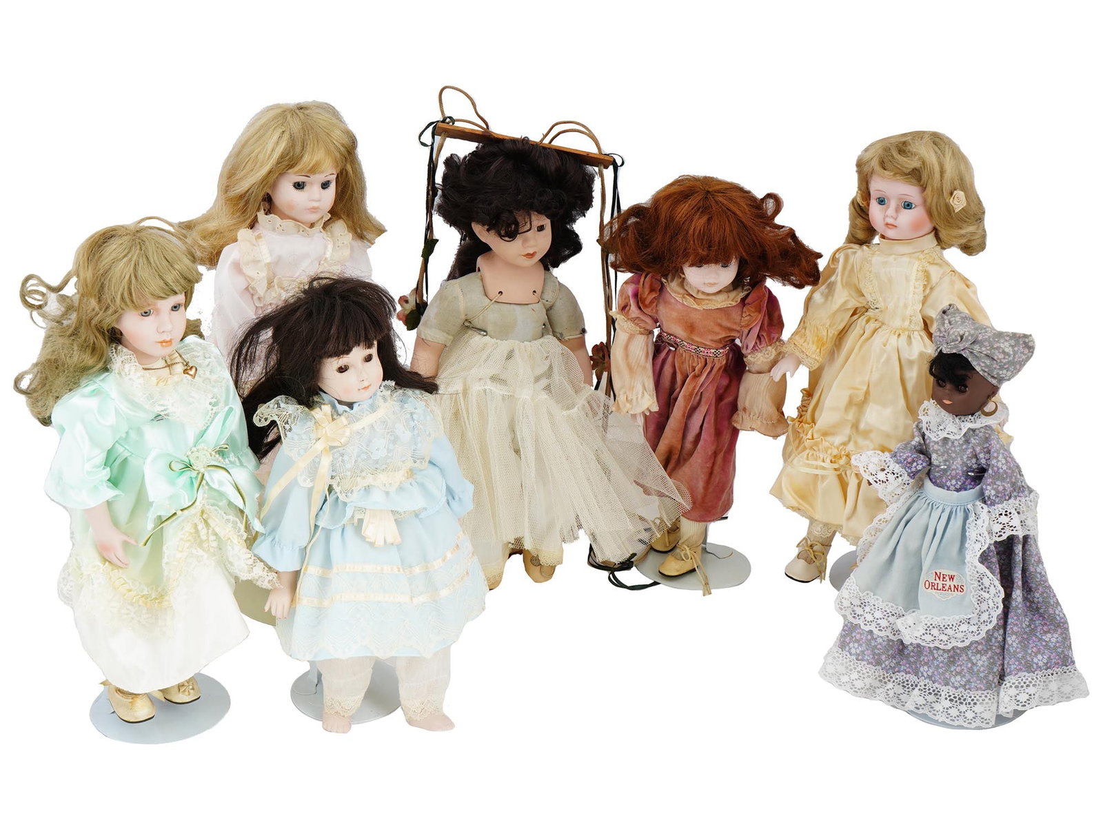 COLLECTION OF VINTAGE PORCELAIN DOLLS IN OUTFITS: A collection of vintage dolls, featuring a variety of shapes and sizes, each adorned with bouffant hairstyles and dressed in exquisite outfits. These dolls, with their distinctive bouffant hairstyles,
