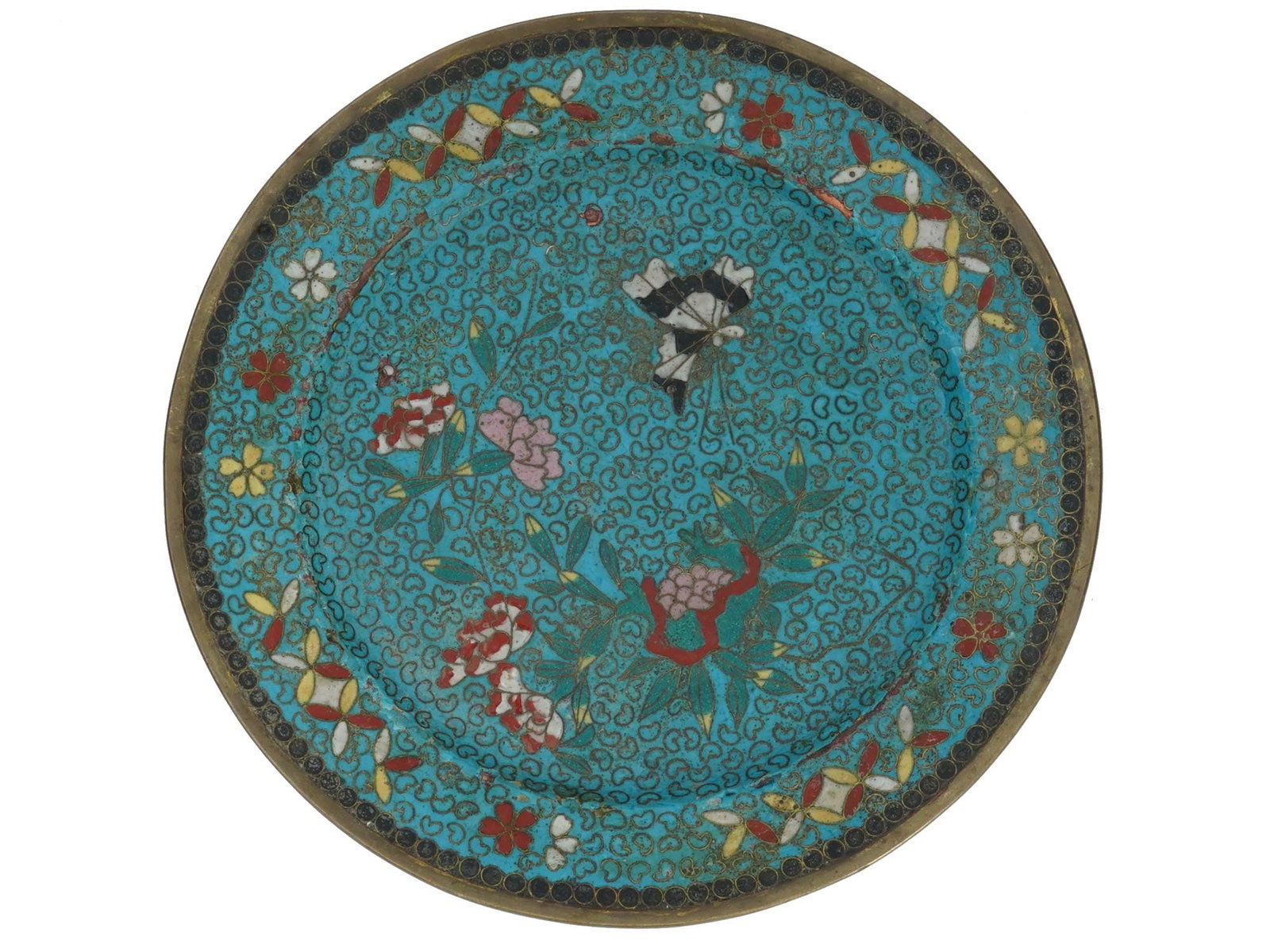 ANTIQUE JAPANESE MEIJI ERA CLOISONNE ENAMEL PLATE: An antique Japanese late Meiji era decorative enamel plate. The interior of the plate is adorned with a polychrome image of a butterfly in blossoming flowers surrounded by floral, foliage and geometri