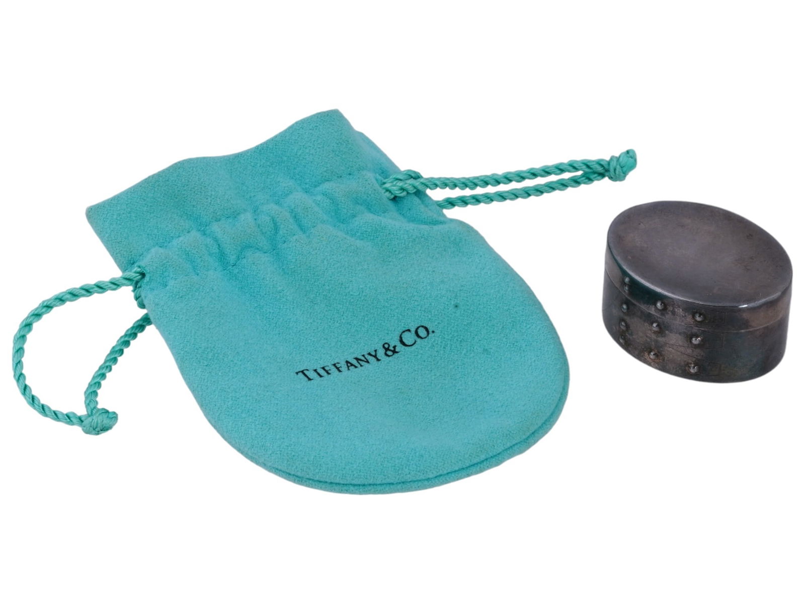 TIFFANY AND CO STERLING SILVER SHAKER PILL BOX: A vintage sterling silver shaker pill box by Tiffany and Co. Oval shape. Hinged lid. Marked Tiffany and Co., Italy, 925 on the bottom. Total Weight: 22 grams. The item comes in original pouch. Collect