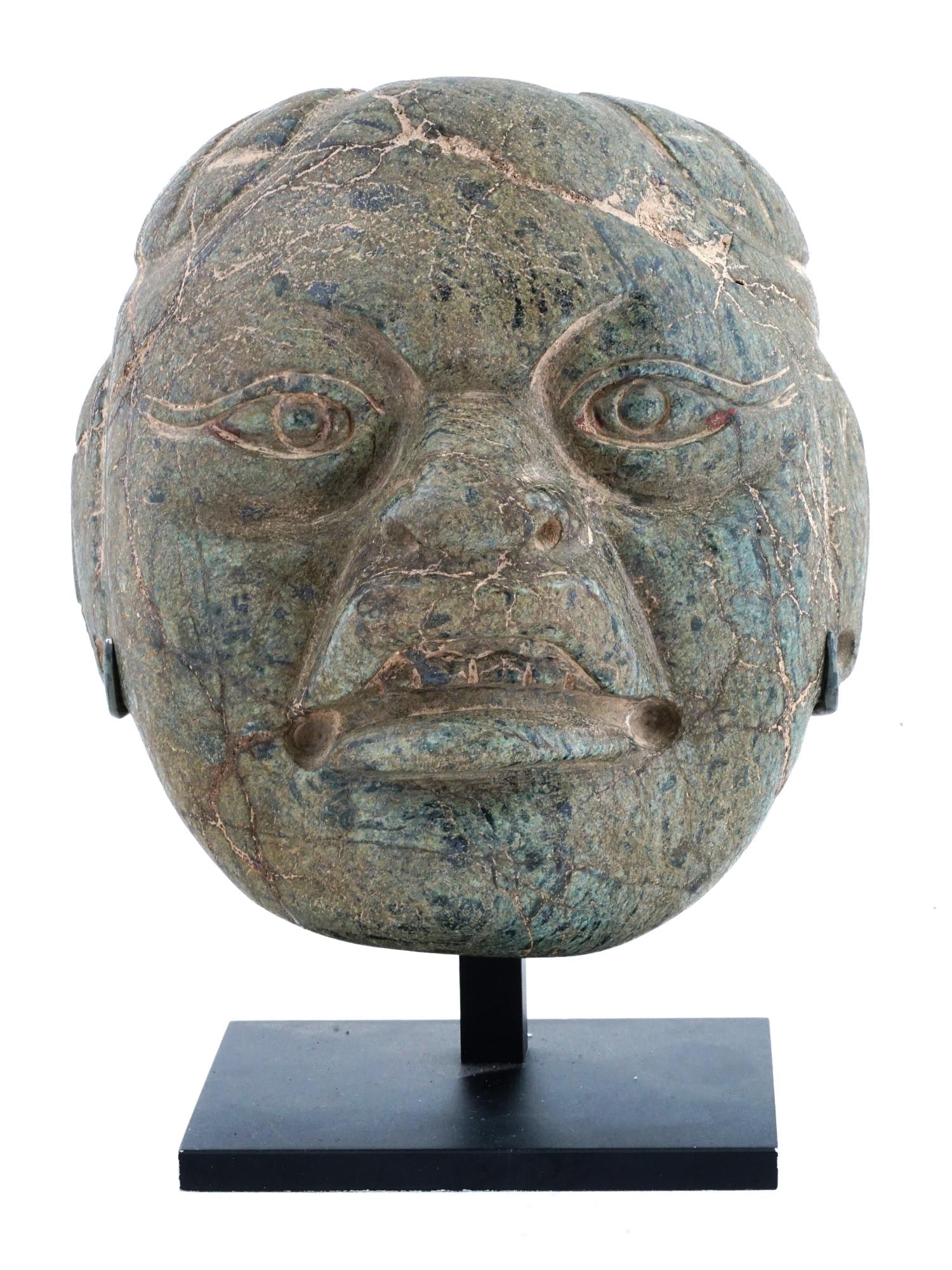 ANCIENT OLMEC CEREMONIAL JADE MASK CA 1100 TO 500 BC: An ancient Olmec ceremonial mask from Pre Columbian America carved of jade. Circa 1100 to 500 BC. The mask represents a male face with a stern, hard expression. The item has well detailed facial featu
