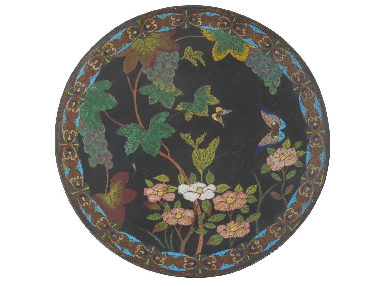 JAPANESE CLOISONNE ENAMEL OVER COPPER CHARGER PLATE: A Japanese enamel over copper plate or charger. The interior of the plate is adorned with a polychrome enamel image of butterflies in grape vines and flowers on the black ground made in the cloisonne 