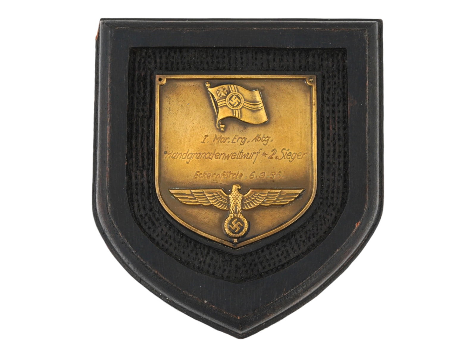 PRE WWII TYPE GERMAN 1936 COMMEMORATIVE WALL PLAQUE: A pre WWII type German 1936 wooden commemorative wall plaque. The black wall plaque is made of wood and has a brass badge in the middle. The brass badge features the German flag with a swastika at the