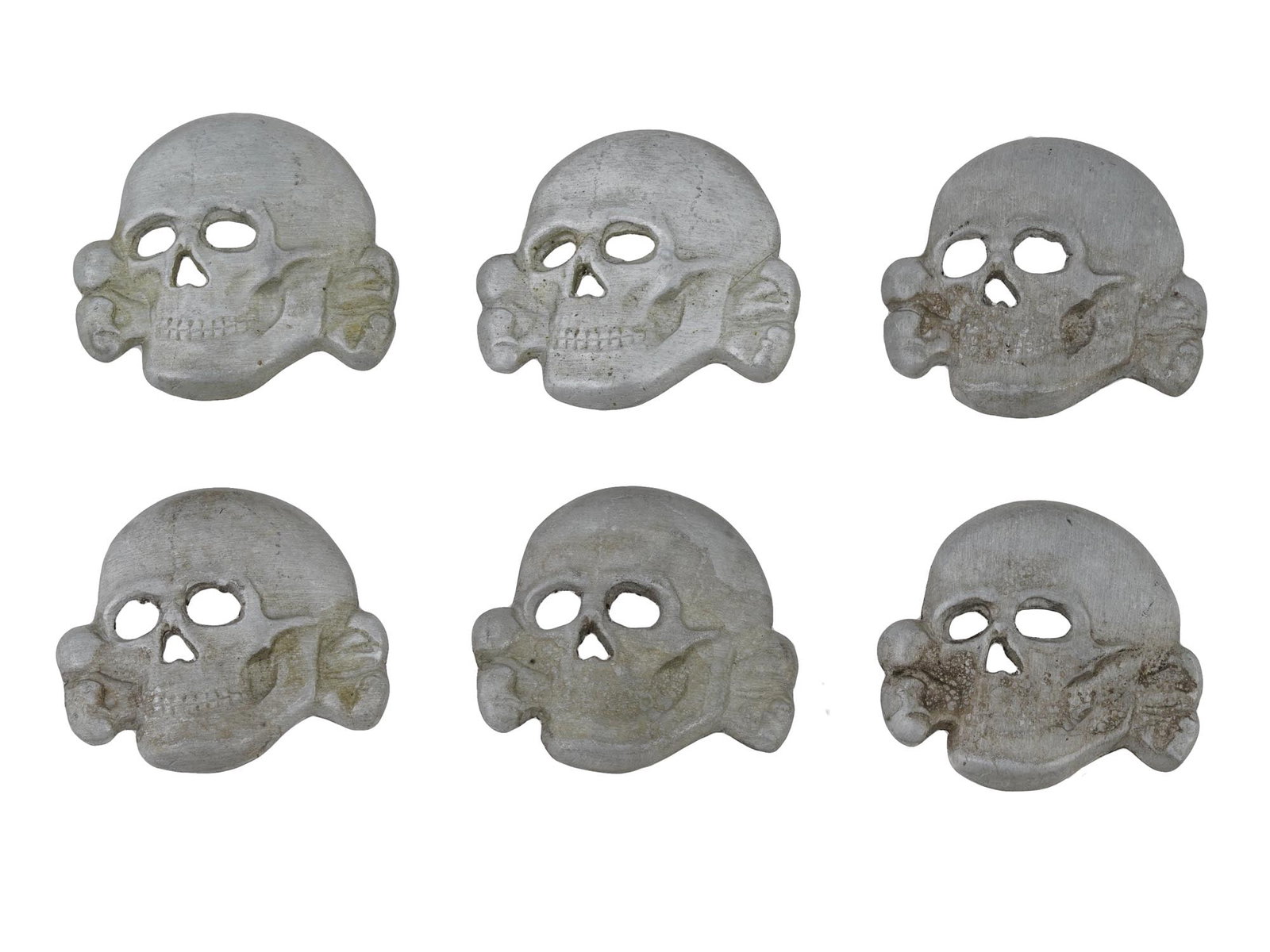 GROUP OF SIX GERMAN WWII TYPE TOTENKOPF INSIGNIAS: A group of six WWII Nazi German Third Reich type Totenkopf Panzer collar tab insignias depicting a skull, engraved with detailed patterns. Marked, RZM mark, on the backside. Second World War Nazi Germ