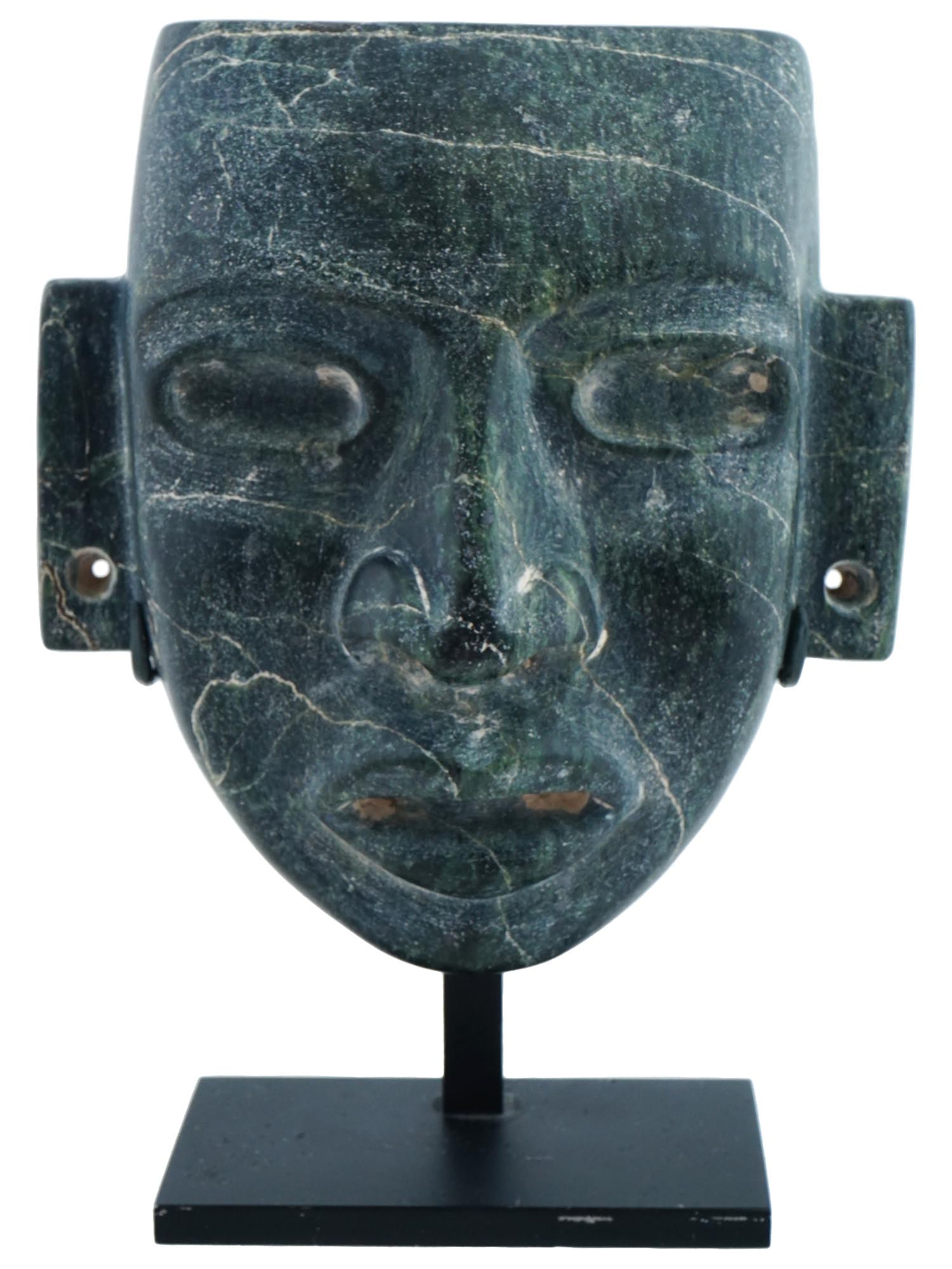 PRE COLUMBIAN AMERICA OLMEC MASK MADE OF DARK JADE: An ancient Olmec mask from Pre Columbian America made of dark green jade. This is a mans face with big eyes and full lips. There are through holes in the earlobes, and there are blind holes on the sid