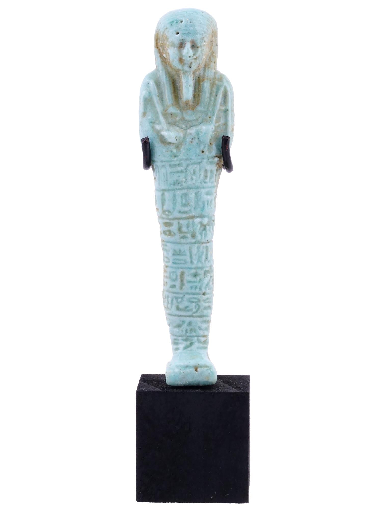 ANCIENT EGYPTIAN FAIENCE USHABTI W BOOK OF DEAD: An ancient Egyptian late glazed faience ushabti with arms crossed over the chest, holding pick and hoe, a column of hieroglyphs running vertically down the front of the body. Book Of The Dead. Covered