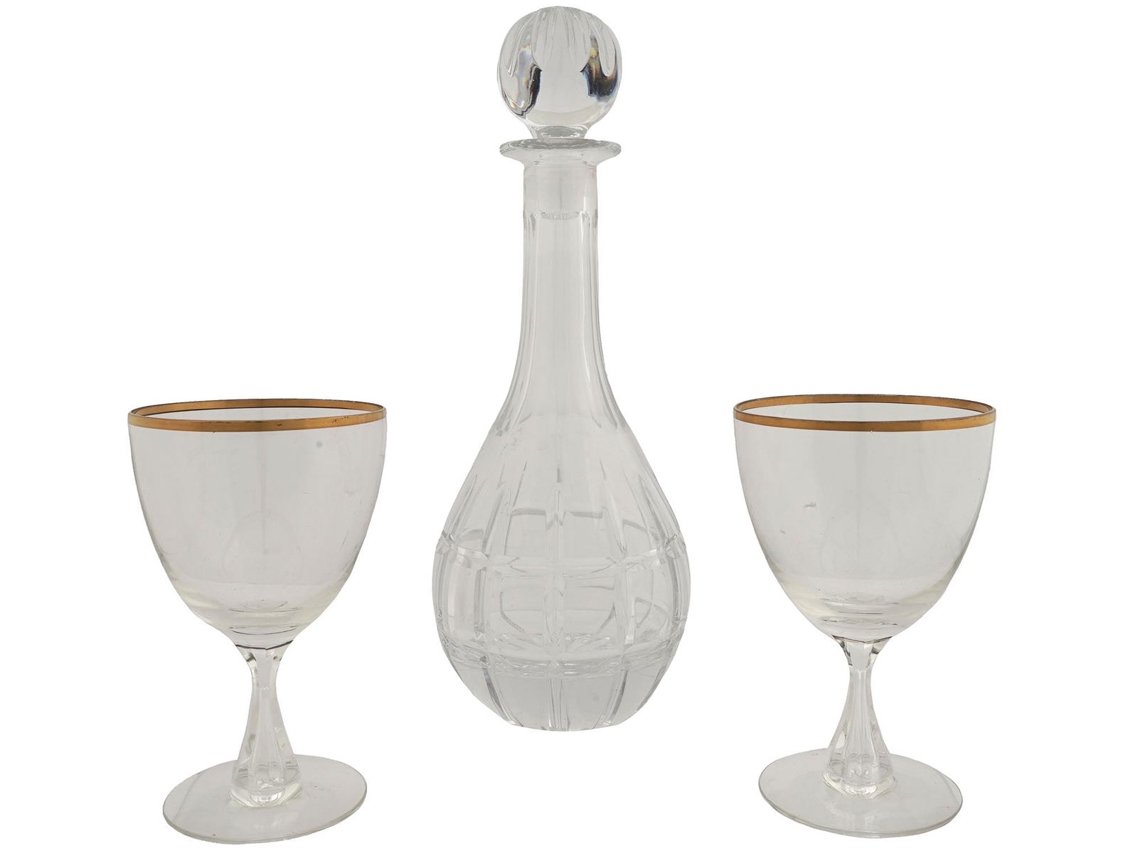 CUT GLASS SET OF DECANTER AND GILT GOBLET GLASSES: A vintage cut glass set of a decanter with a sphere shaped stopper and a pair of goblet glasses. The decanter is adorned with cut geometrical and floral designs. The goblet glasses feature gilded rims