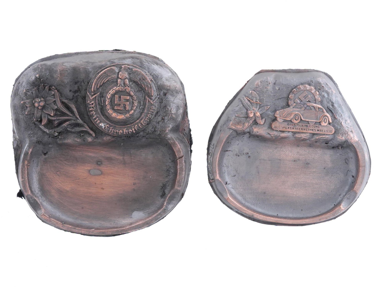 WWII MODEL NAZI GERMAN THIRD REICH ASHTRAYS: A lot of two WWII model Nazi German Third Reich ashtrays. The lot includes Waffen SS ashtrays, featuring relief images representing an edelweiss flower, a Nazi eagle clutching a swastika insignia, and
