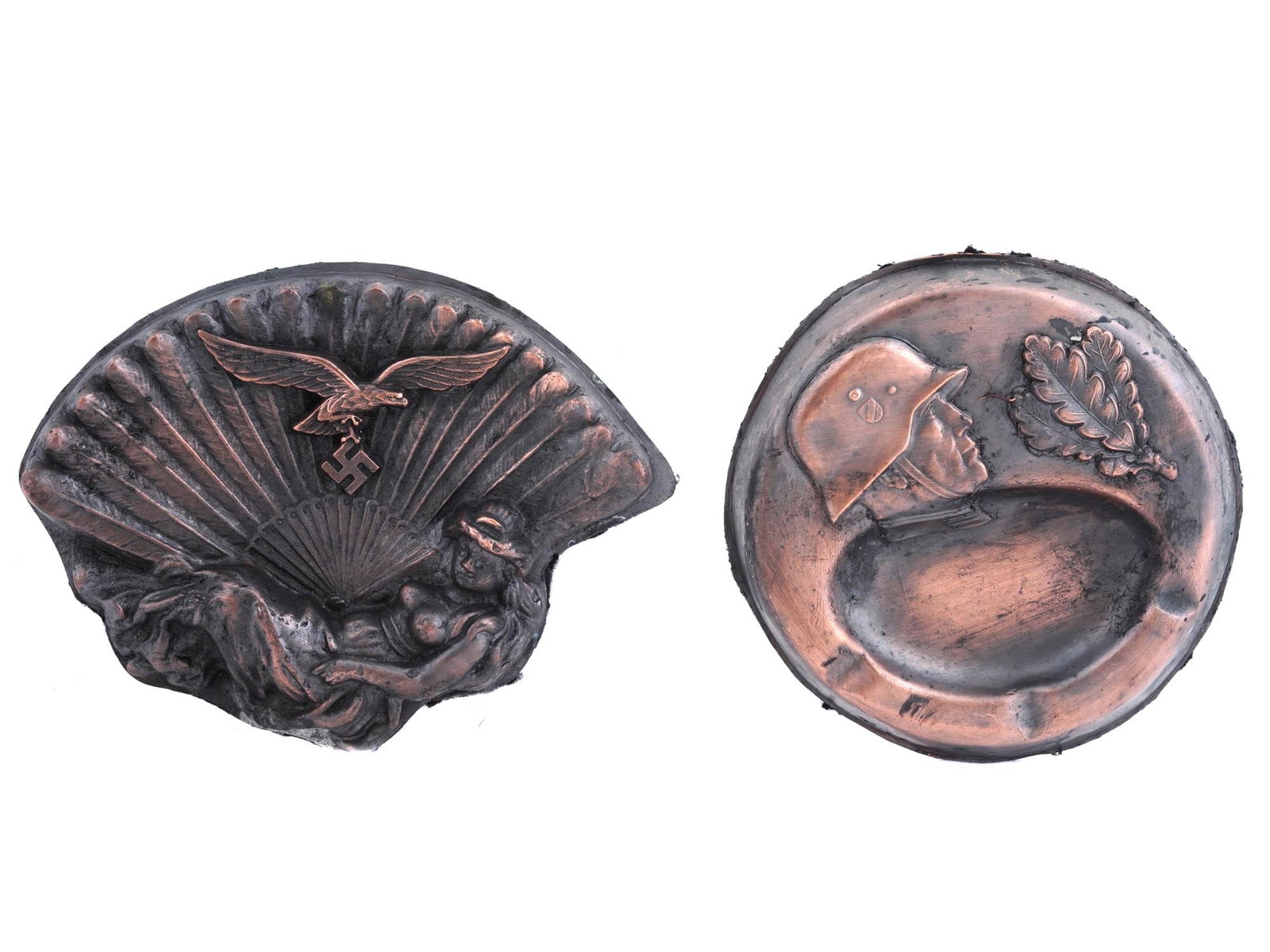 WWII MODEL NAZI GERMAN THIRD REICH ASHTRAYS: A lot of two WWII model Nazi German Third Reich ashtrays. The first ashtray features a lying woman and a flying Nazi eagle with a swastika against the backdrop of an extra large fan. The second ashtra
