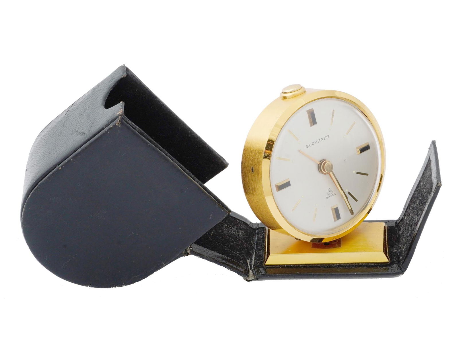 SWISS BUCHERER TRAVEL ALARM CLOCK IN LEATHER CASE: A Mid 20th century Swiss Bucherer travel alarm clock. A white enamelled dial with gold tone numerals and hands. Marked with a brand logo on the dial. Presented in an original folding leather case. Mar