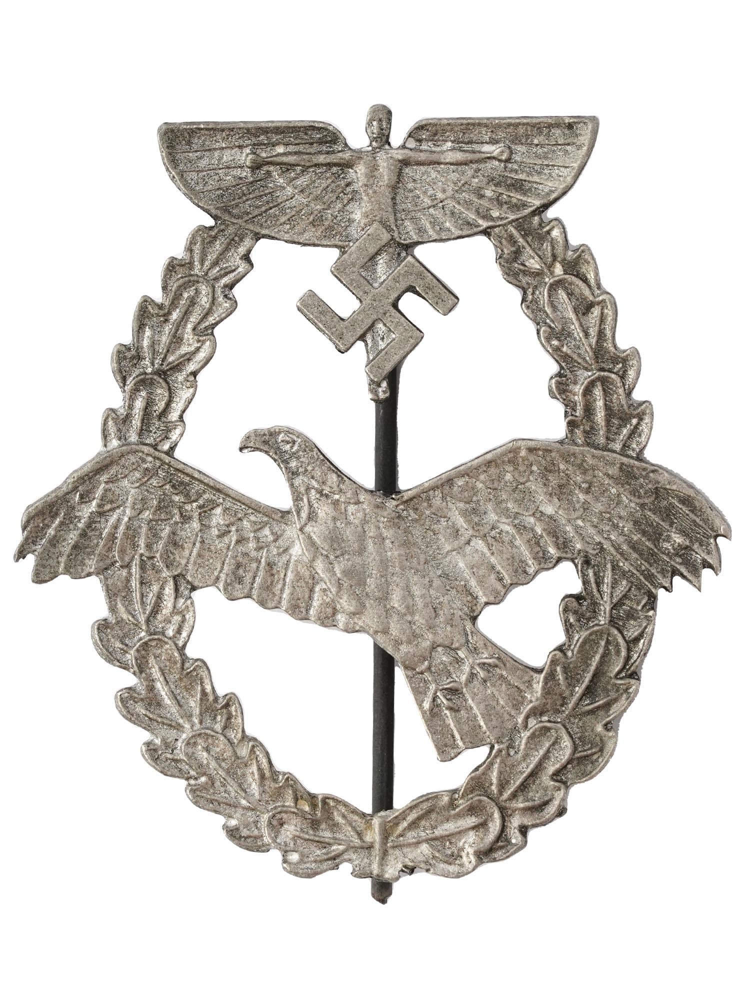 WWII NAZI GERMAN THIRD REICH ERA NSFK PILOTS BADGE: A World War II Nazi German Third Reich NSFK Pilots badge. The badge is adorned with a relief image of a Nazi eagle, an oak wreath, and a human with stretched wings and a swastika insignia. Second Worl