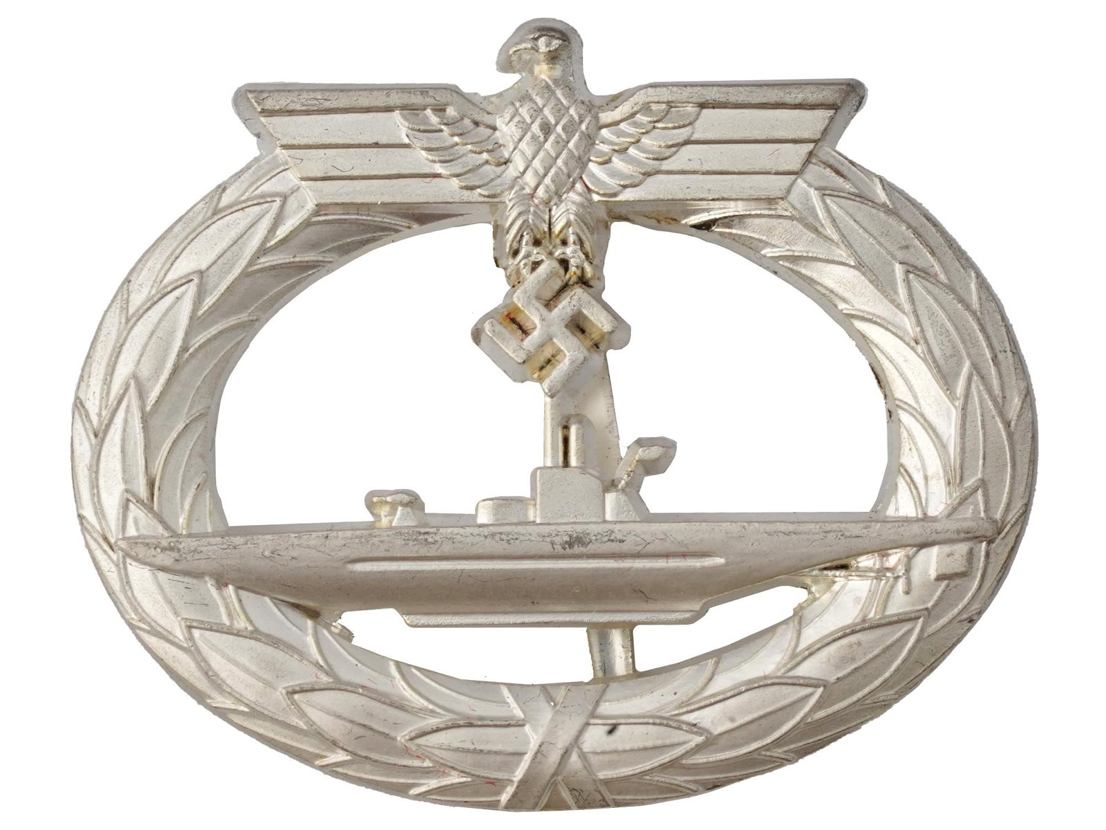 WWII NAZI GERMAN THIRD REICH KRIEGSMARINE U BOAT BADGE: A WWII Nazi German Kriegsmarine U-Boat badge. Featuring an oval laurel leaf wreath joined at the bottom by a ribbon, topped by a Wehrmacht eagle clutching a mobile swastika, the badge includes a centr