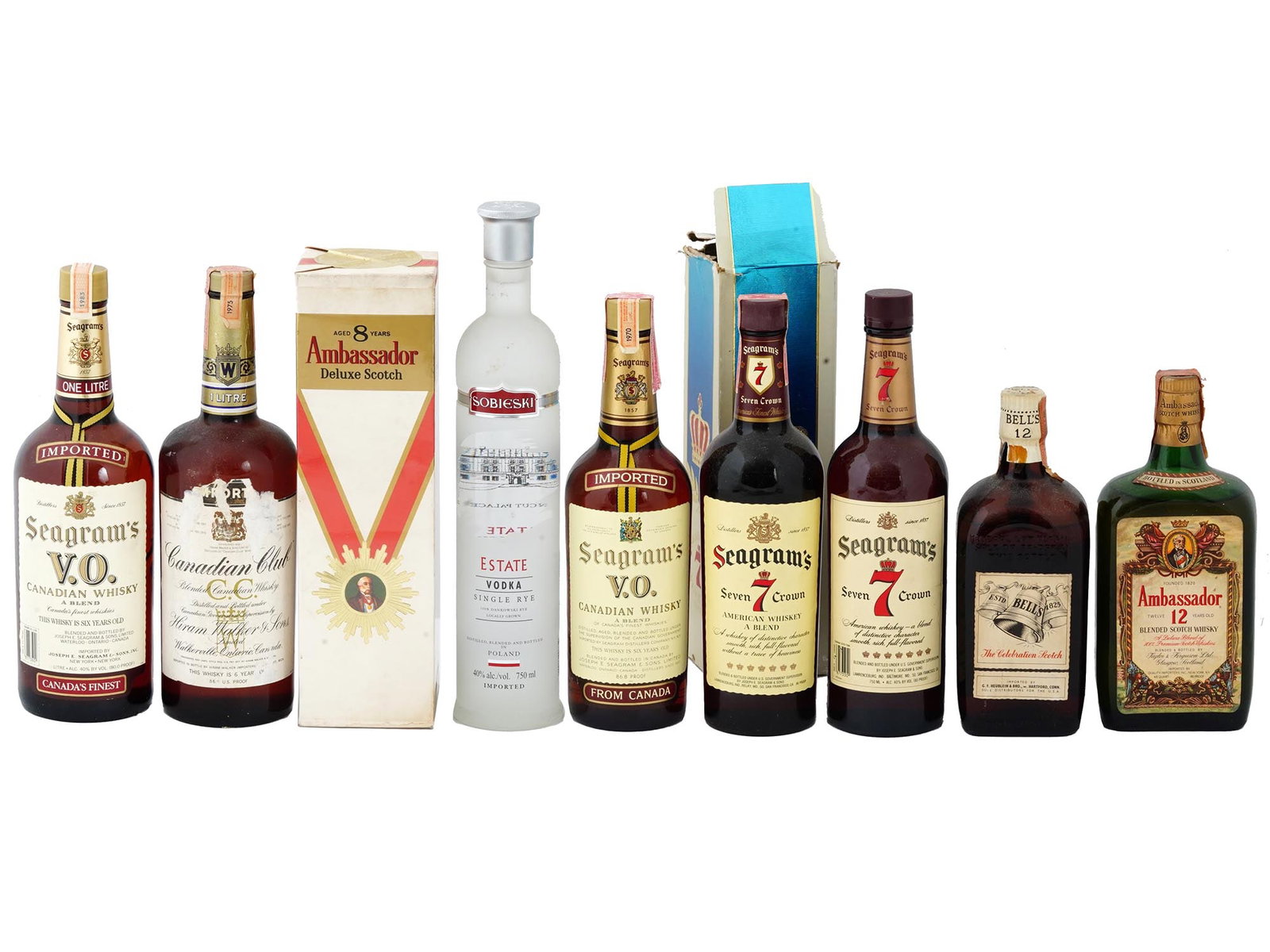 COLLECTION OF VINTAGE ALCOHOL SEALED WHISKY BOTTLES: A collection of nine sealed alcohol bottles. The collection includes a group of Seagrams bottles, Seven Crown, V.O.; Ambassador Deluxe Scotch; Estate Vodka; and others. Several bottles are presented i