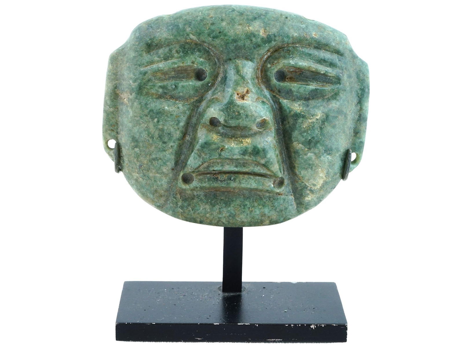 ANCIENT PRE COLUMBIAN AMERICA JADE OLMEC MASK: An ancient Olmec mask from Pre Columbian America made of green jade. The male mask has harshly carved facial features, and eyes with drilling holes in the corners. The same drill slits are in the nose