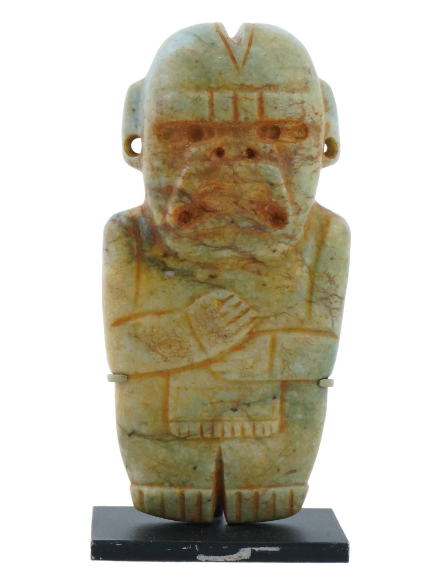 ANCIENT OLMEC STONED IDOL PRE COLUMBIAN AMERICA: An ancient Olmec idol from Pre Columbian America carved of green colored stone, presumably jade. The sculpture depicts a male figurine with elongated eyes, hands resting above the knees across the bod