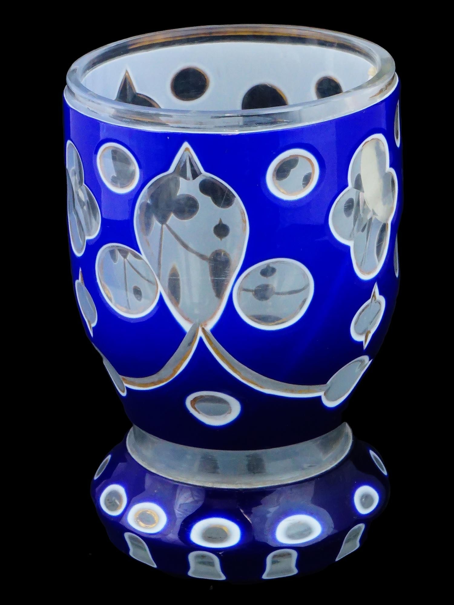 ANTIQUE BOHEMIAN BIEDERMEIER BLUE WHITE GLASS BEAKER: An antique Biedermeier glass beaker, characterized by a widened rim, narrowed middle, and round base. The beaker is cut and overlaid with blue and white opal glass, featuring transparent recesses for