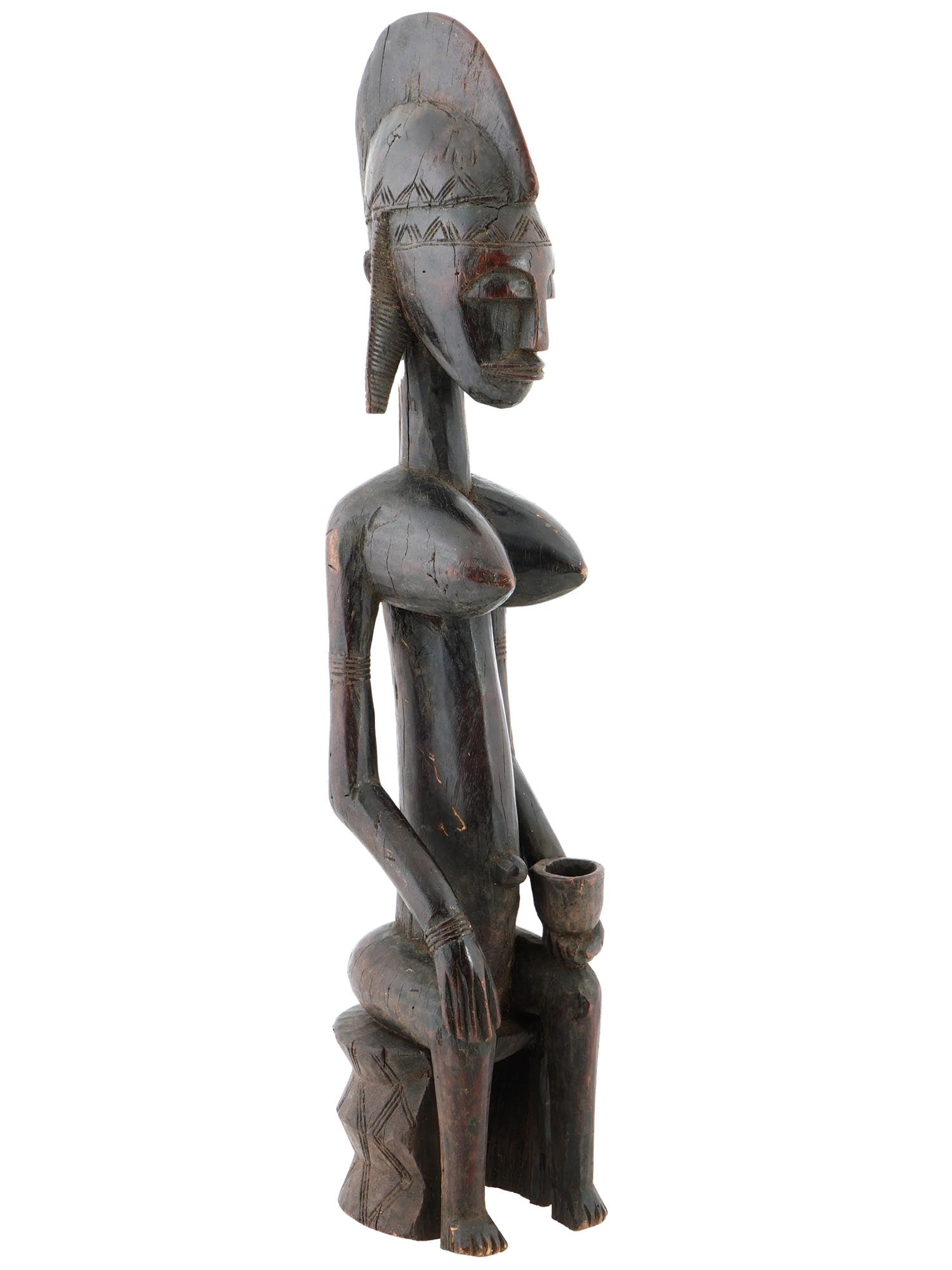 WEST AFRICAN SENEFU PEOPLE FUNERAL RITUAL FIGURE: A traditional African Senefu people funeral ritual figure from Ivory Coast. Crafted from wood with meticulous attention to detail, it features a hand carved female figure sitting on a chair with a cup